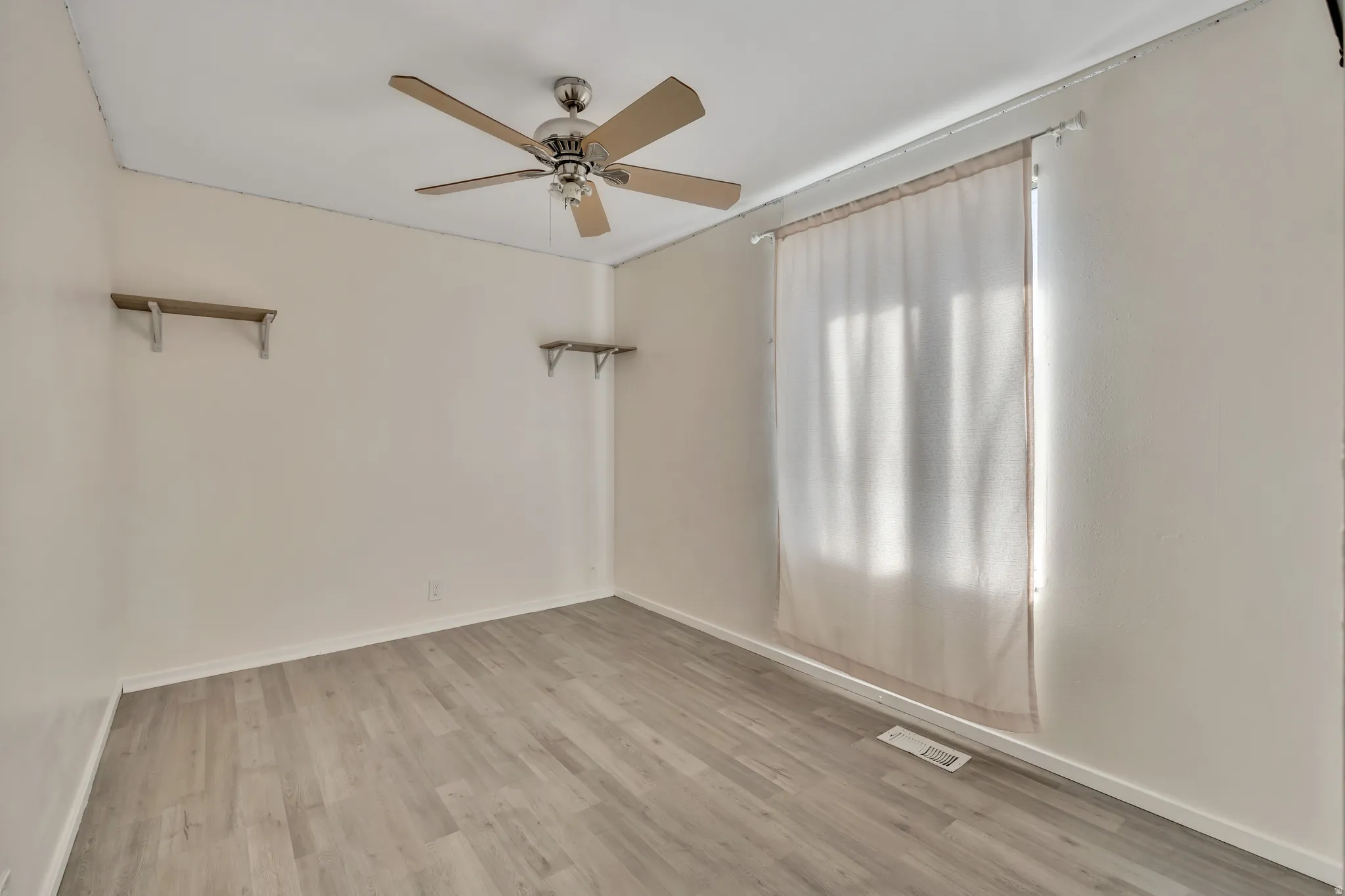 Unfurnished room featuring light wood-style flooring and ceiling fan