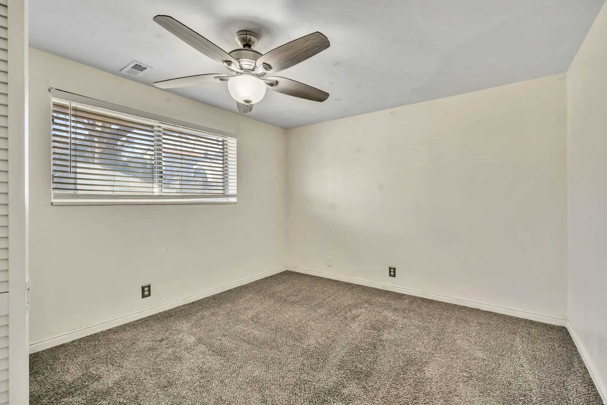Empty room with dark colored carpet and ceiling fan