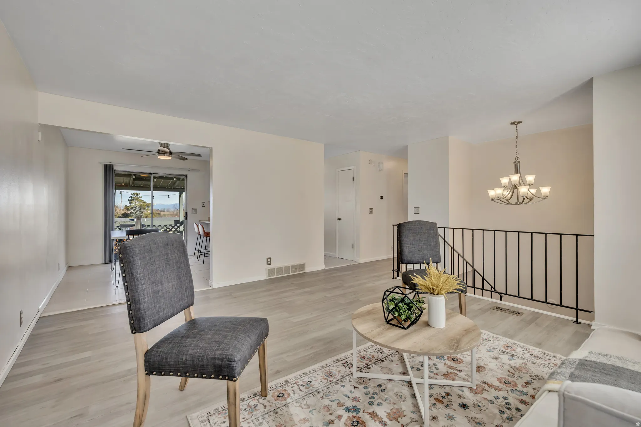 Living room featuring light wood-style flooring, hanging lights, and ceiling fan