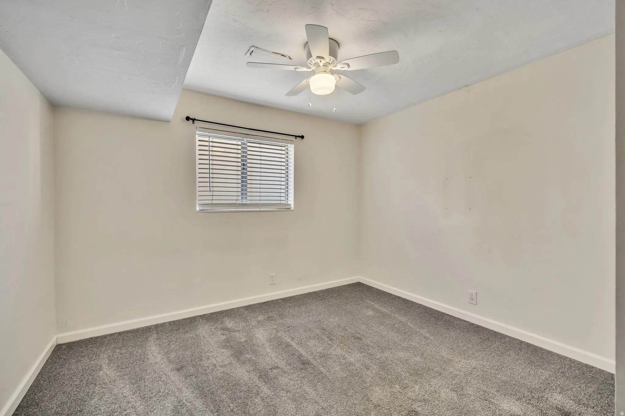 Carpeted spare room with baseboards and a ceiling fan