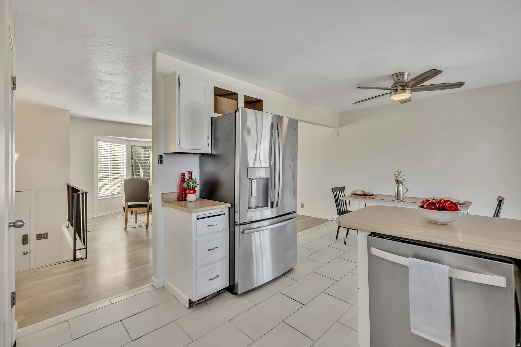 Kitchen featuring stainless steel appliances, white cabinetry, ceiling fan, butcher block countertops, and light tile patterned floors