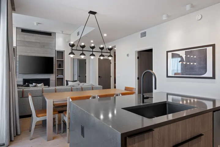 Kitchen featuring open floor plan, dark stone countertops, a center island with sink, a fireplace, and modern cabinets