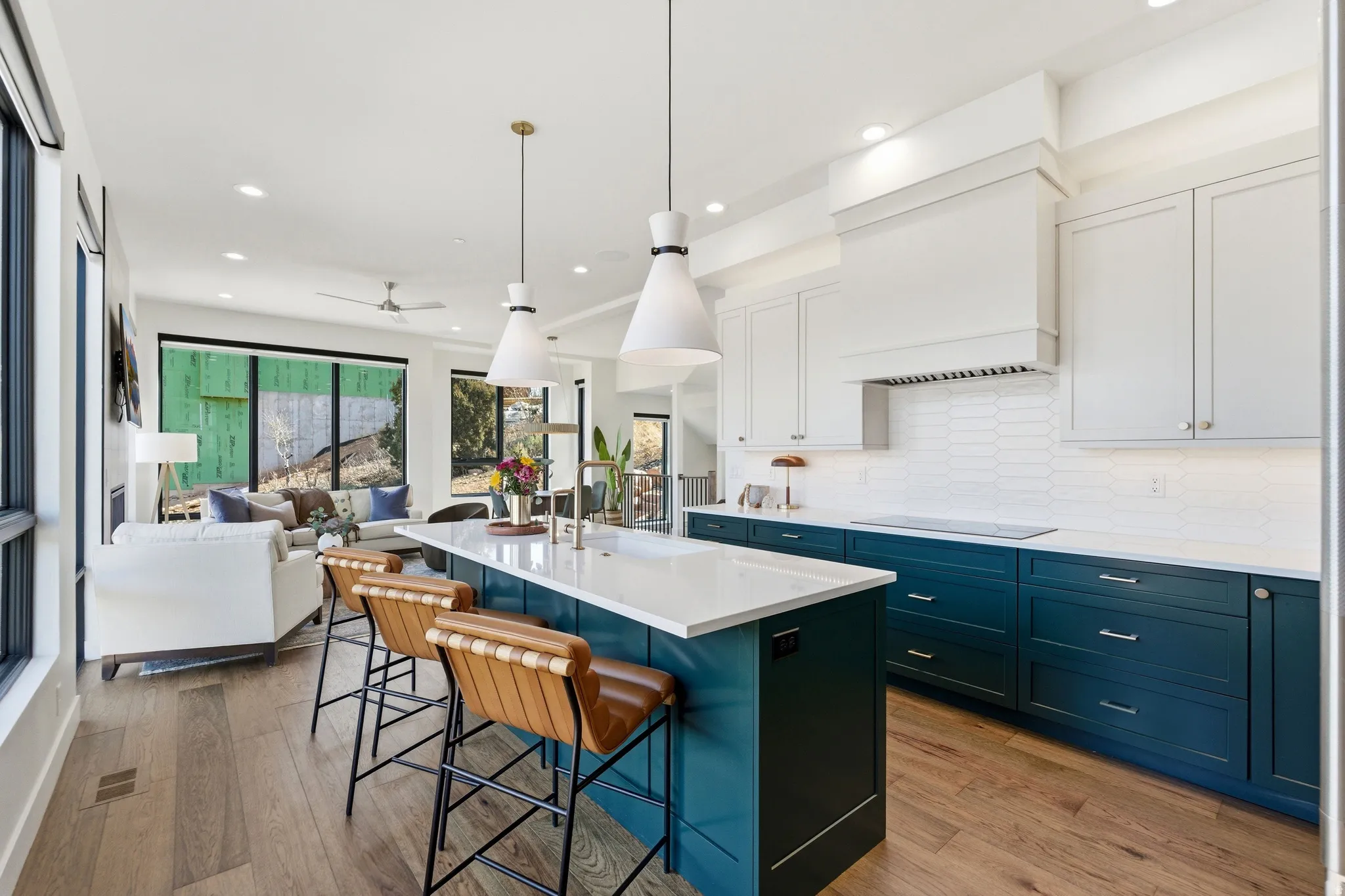 Two tone kitchen with two tone cabinetry, a kitchen breakfast bar, a kitchen island with sink, light wood-style floors, and decorative light fixtures