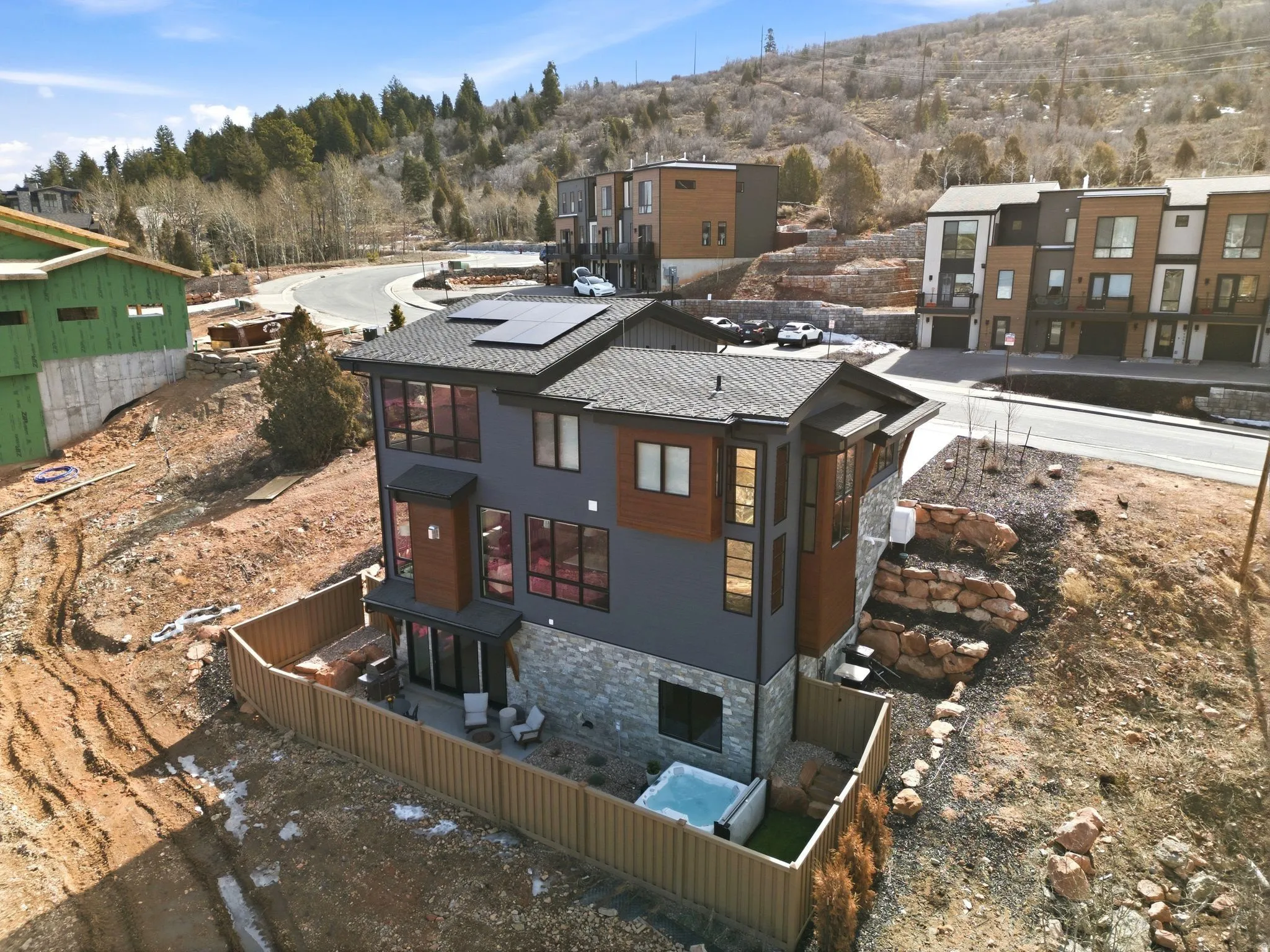 Rear view of property with roof mounted solar panels, a fenced backyard, stone siding, and a patio