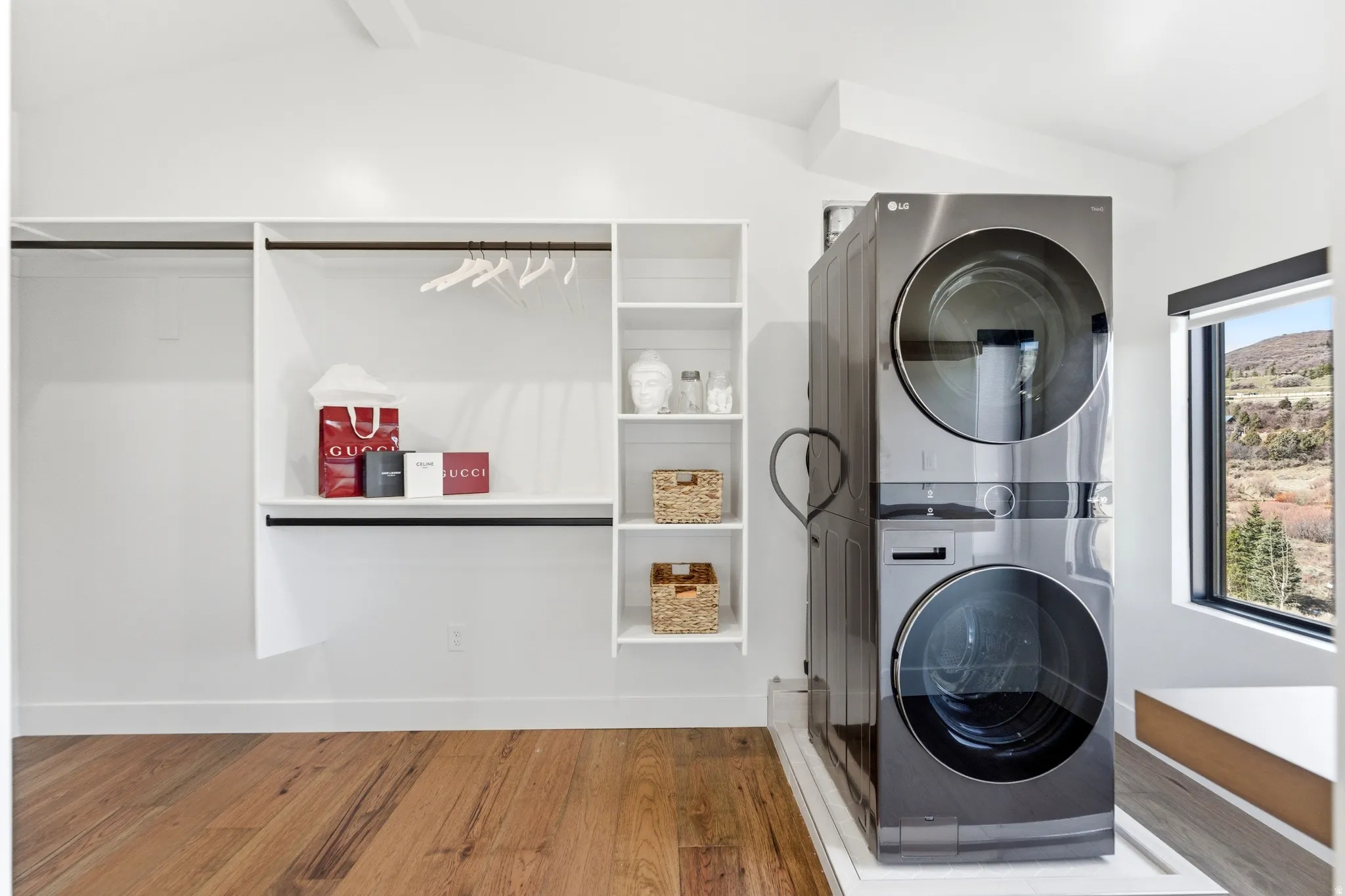 Laundry area with light wood finished floors and stacked washer and clothes dryer