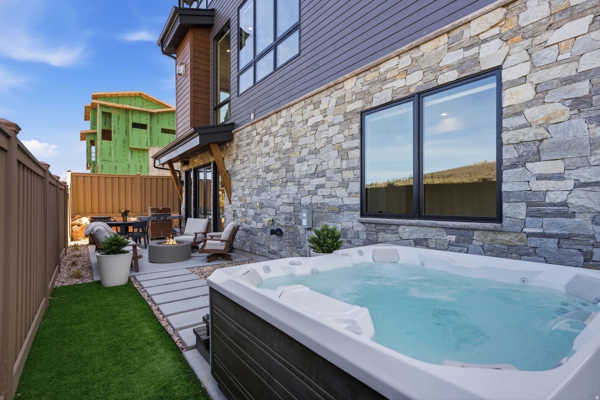 Fenced backyard featuring a patio area, a hot tub, grilling area, and an outdoor fire pit