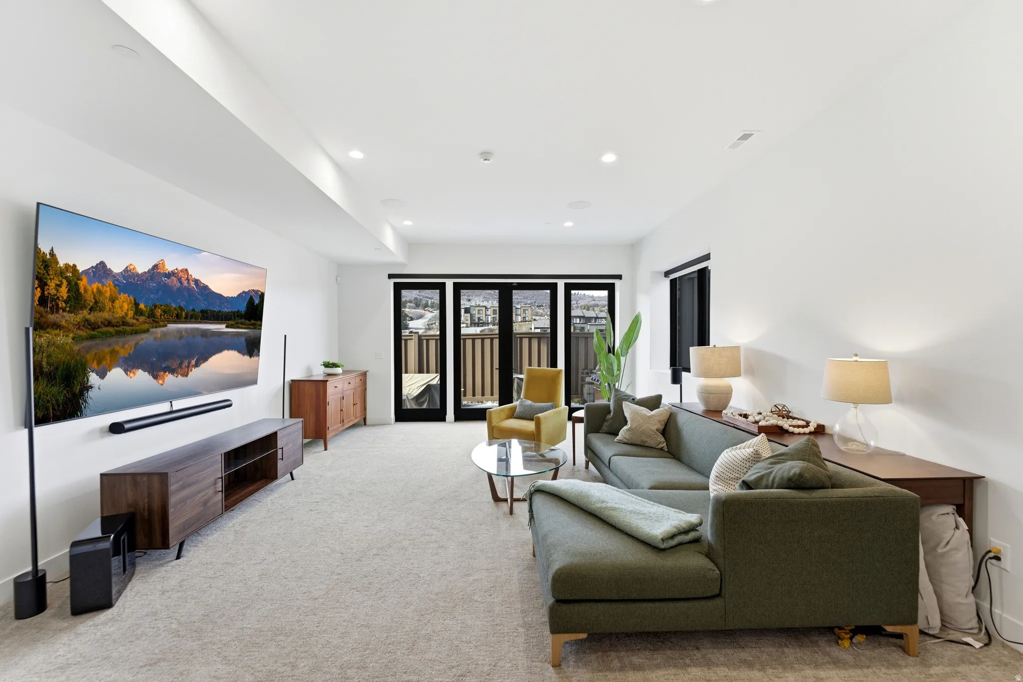 Living area with light carpet and recessed lighting