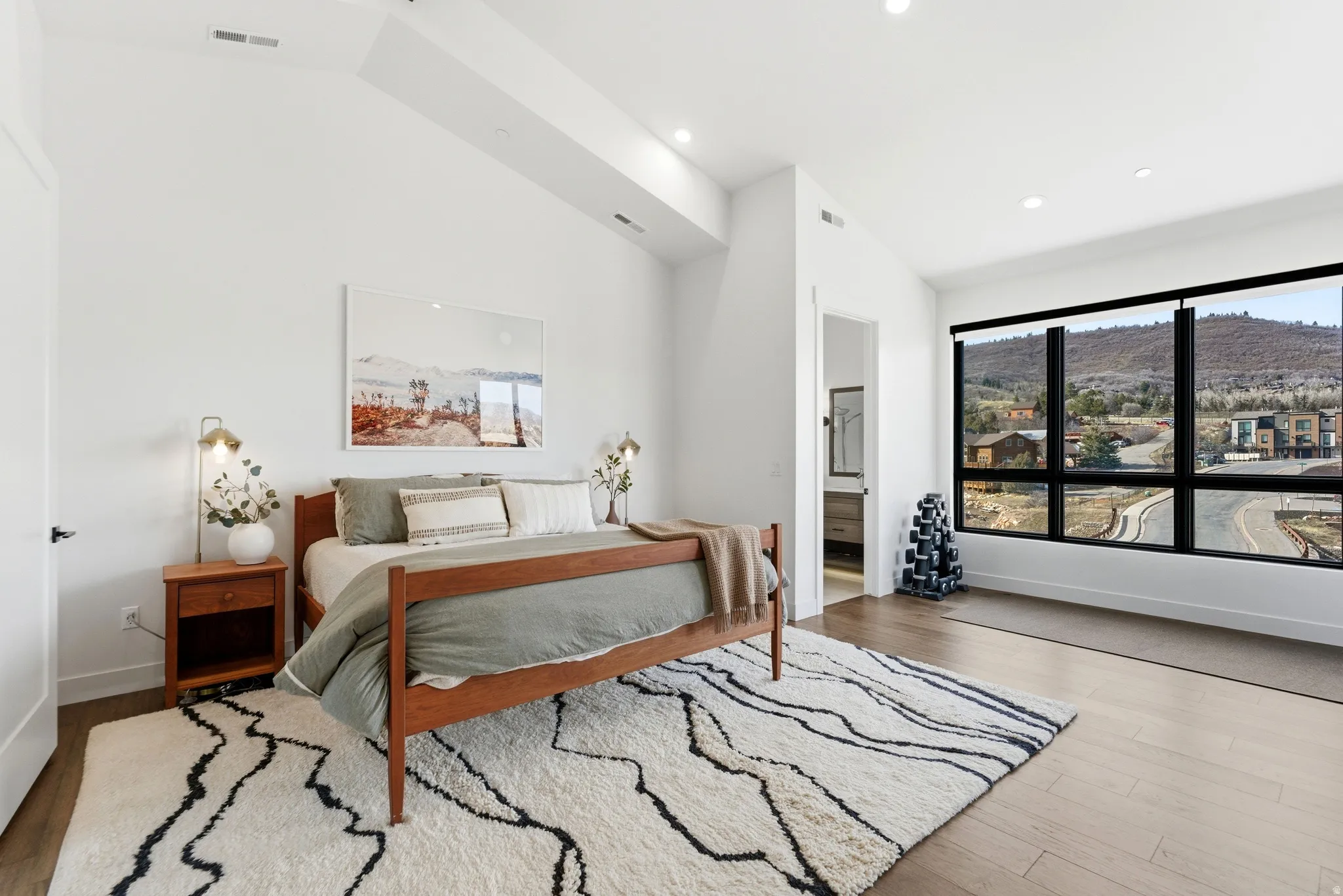 Bedroom featuring a mountain view, vaulted ceiling, ensuite bath, wood finished floors, and recessed lighting