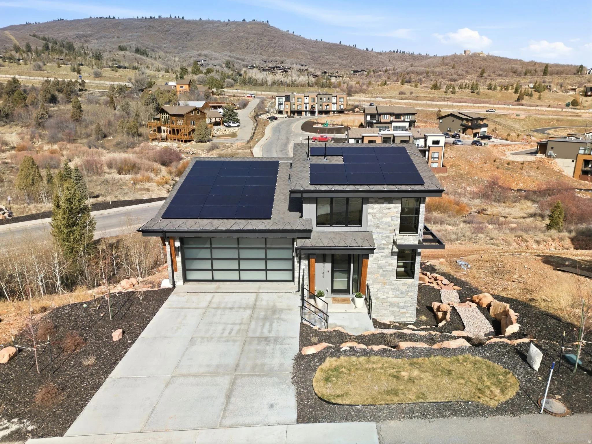 Contemporary home with roof mounted solar panels, driveway, an attached garage, a mountain view, and a residential view