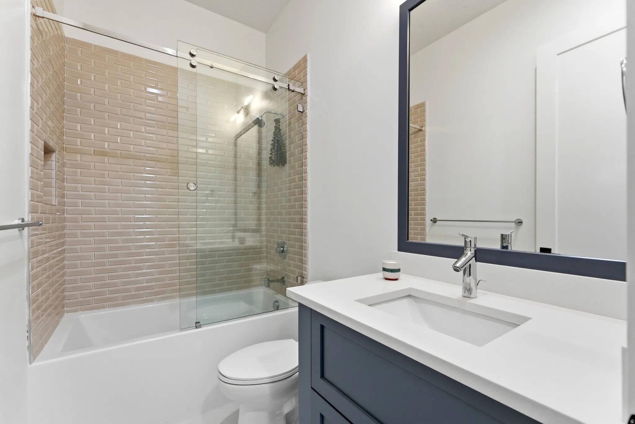 Bathroom featuring vanity and shower / bath combination with glass door