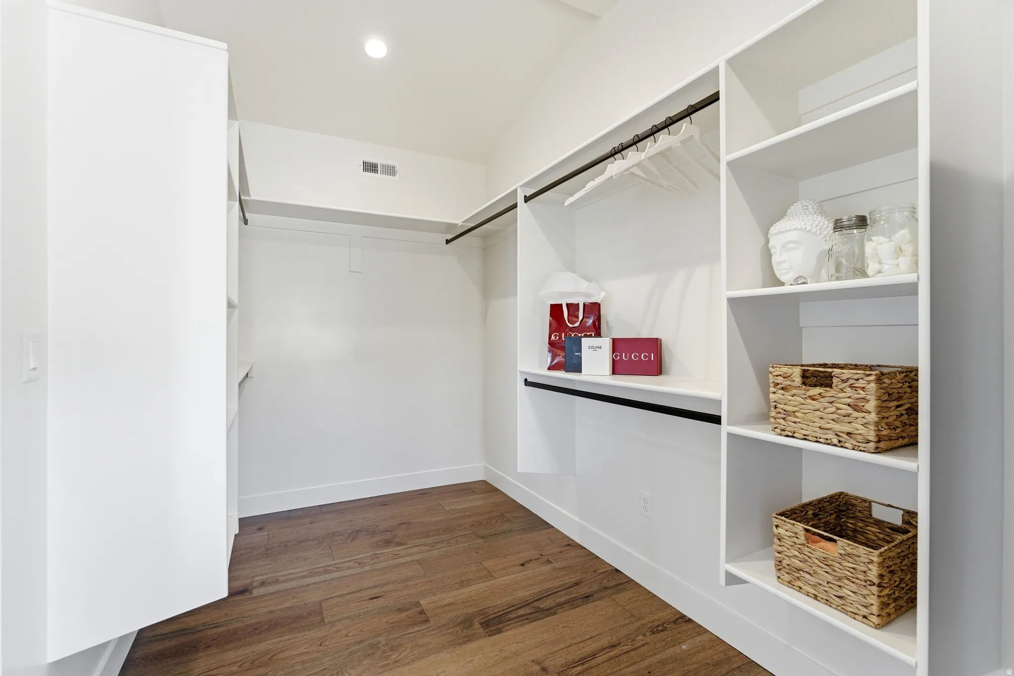 Walk in closet with dark wood finished floors