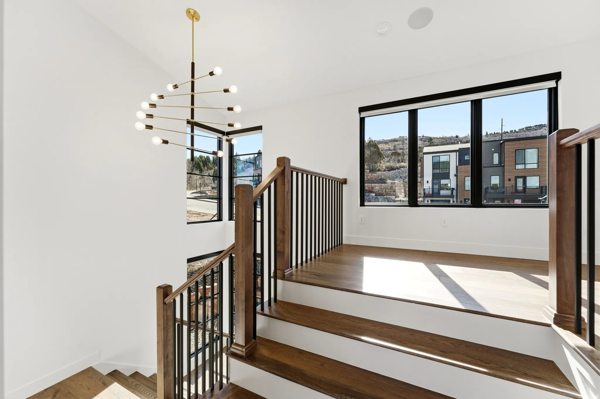 Stairway featuring plenty of natural light, wood finished floors, and a chandelier