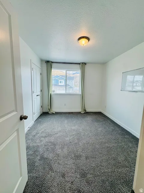 Empty room featuring carpet floors and a textured ceiling