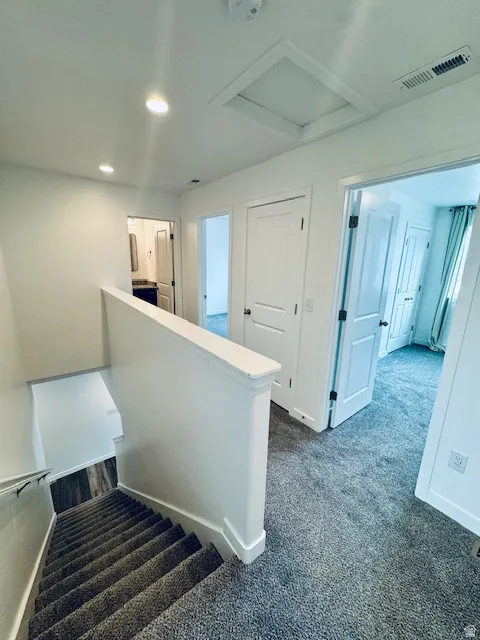 Staircase with carpet floors and recessed lighting