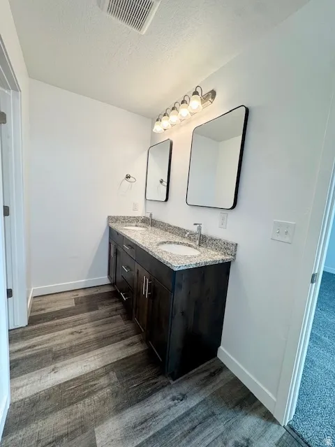 Bathroom featuring double vanity and a textured ceiling