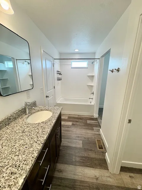 Full bath featuring vanity, dark wood-style floors, shower / bath combination, and a textured ceiling