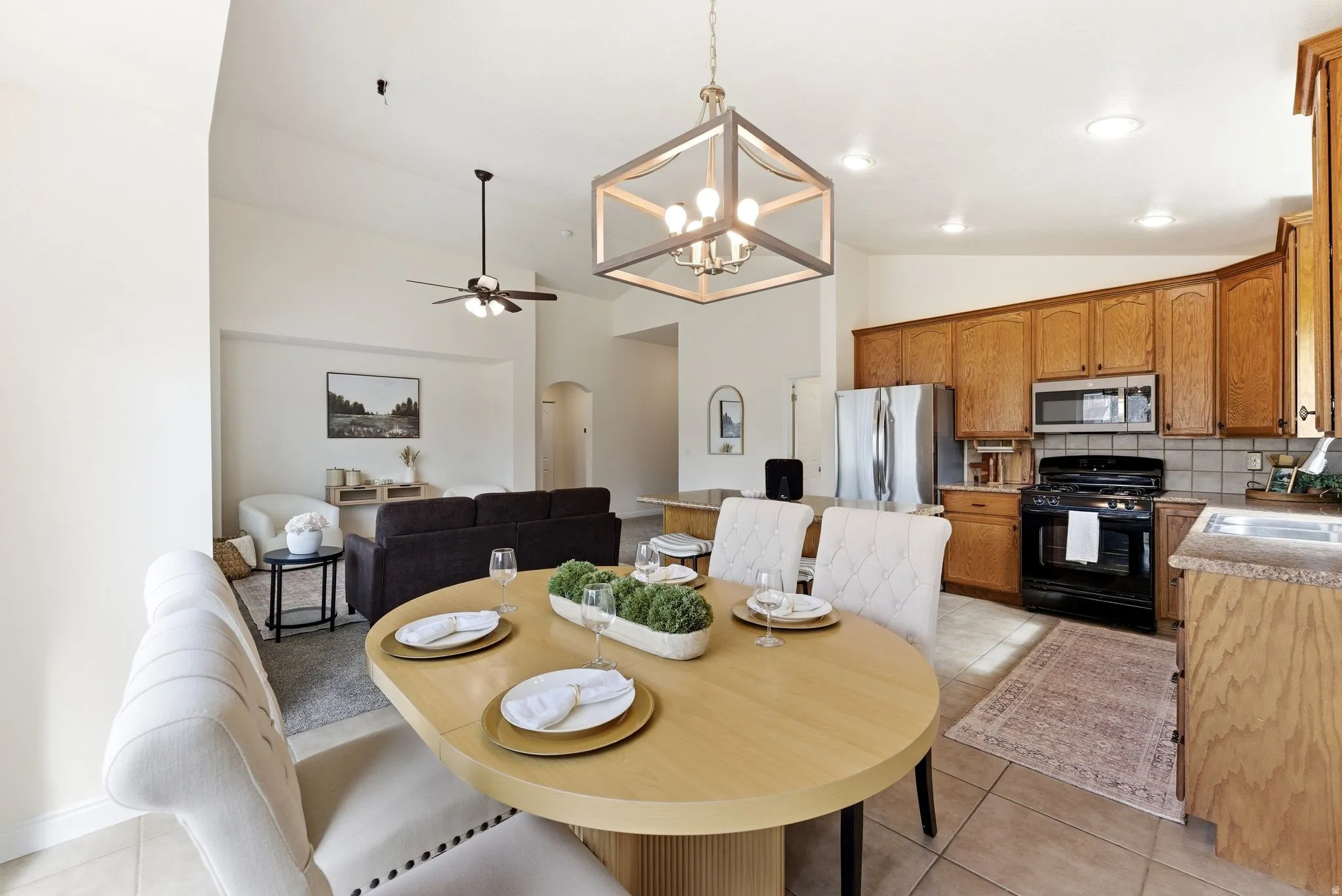 Dining area featuring a ceiling fan, hanging lights, arched walkways, light tile patterned floors, and lofted ceiling