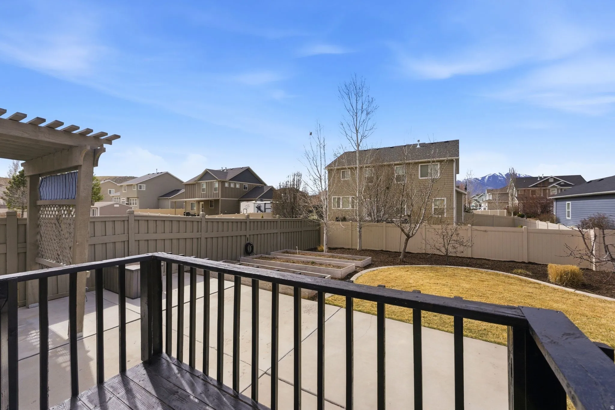 Wooden terrace with a residential view, a fenced backyard, a patio area, and a vegetable garden
