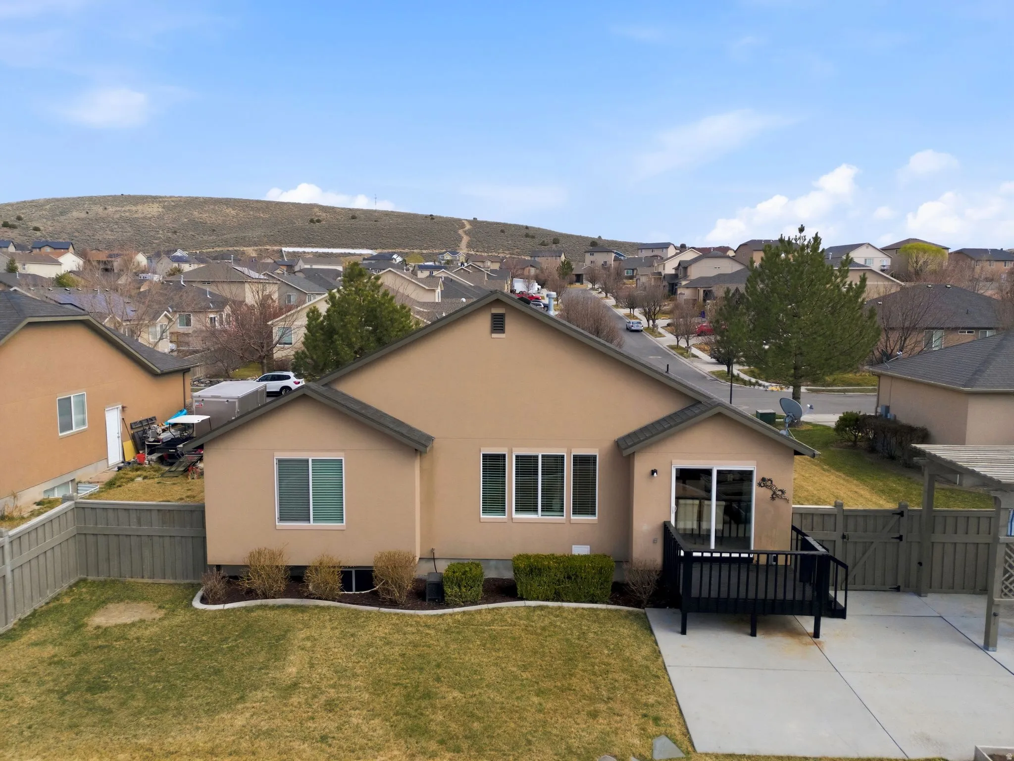 Back of house with a gate, stucco siding, a residential view, a fenced backyard, and a patio