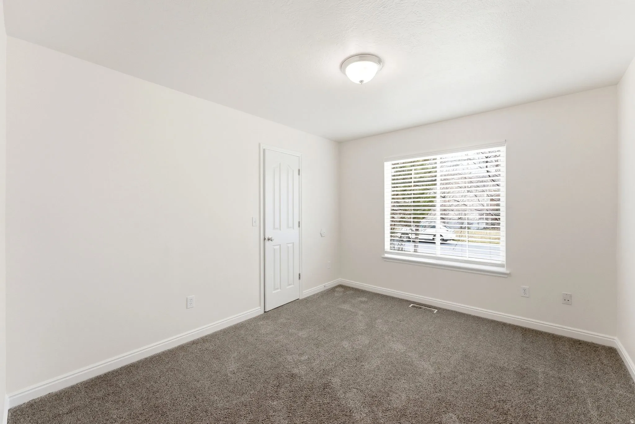 Empty room featuring baseboards and dark colored carpet