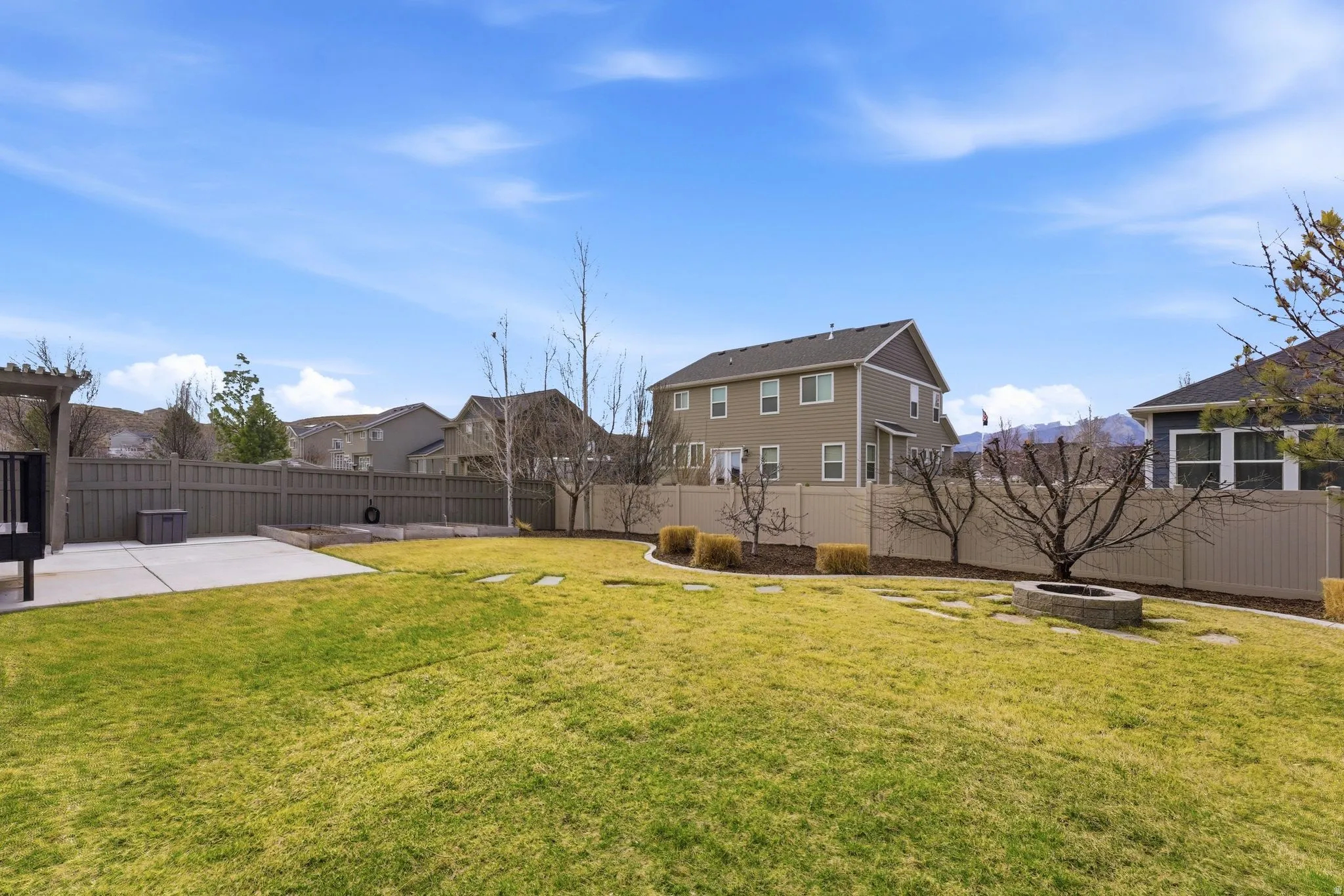 Fenced backyard with an outdoor fire pit, a patio area, and a residential view