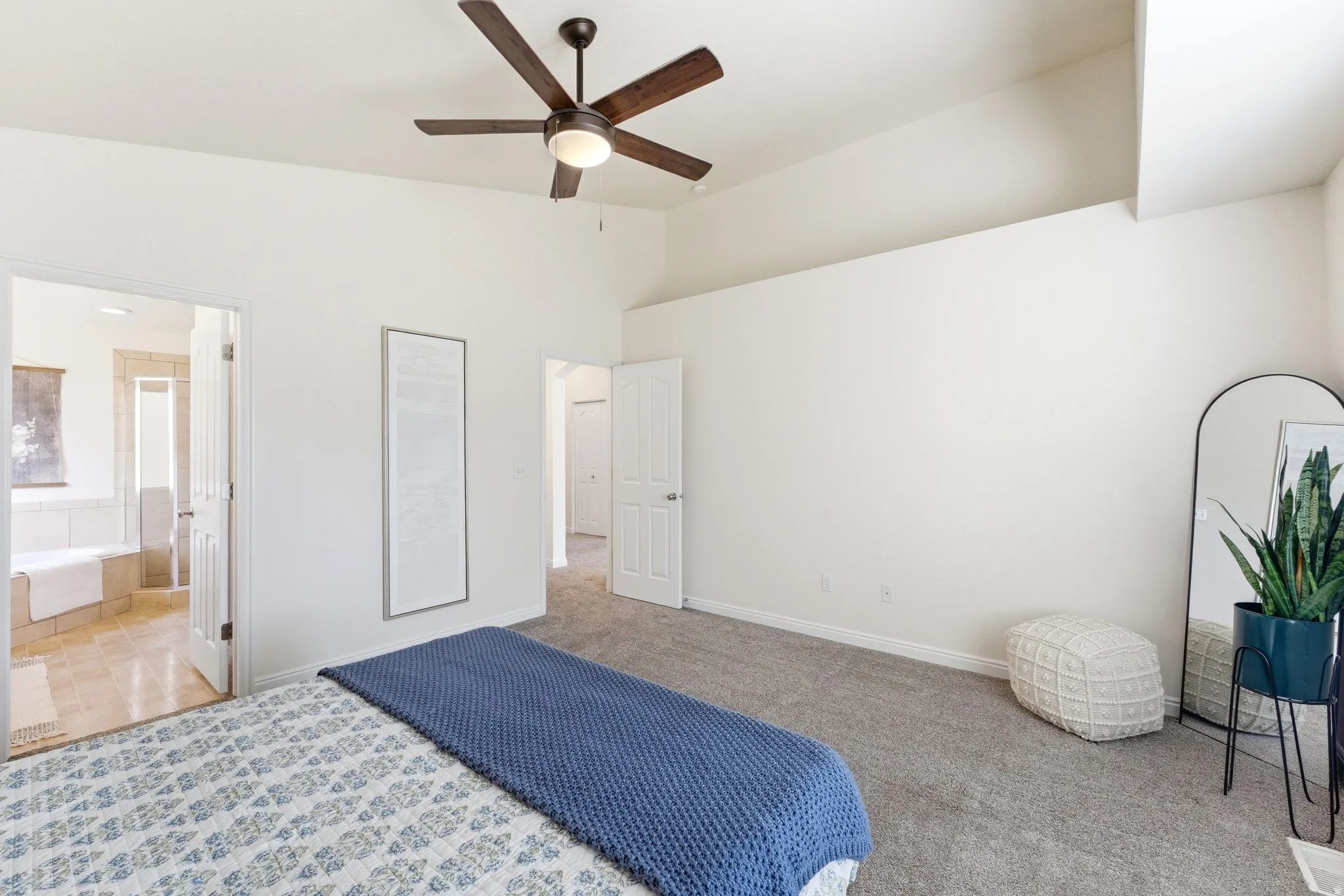 Unfurnished bedroom with light colored carpet, ceiling fan, vaulted ceiling, and connected bathroom