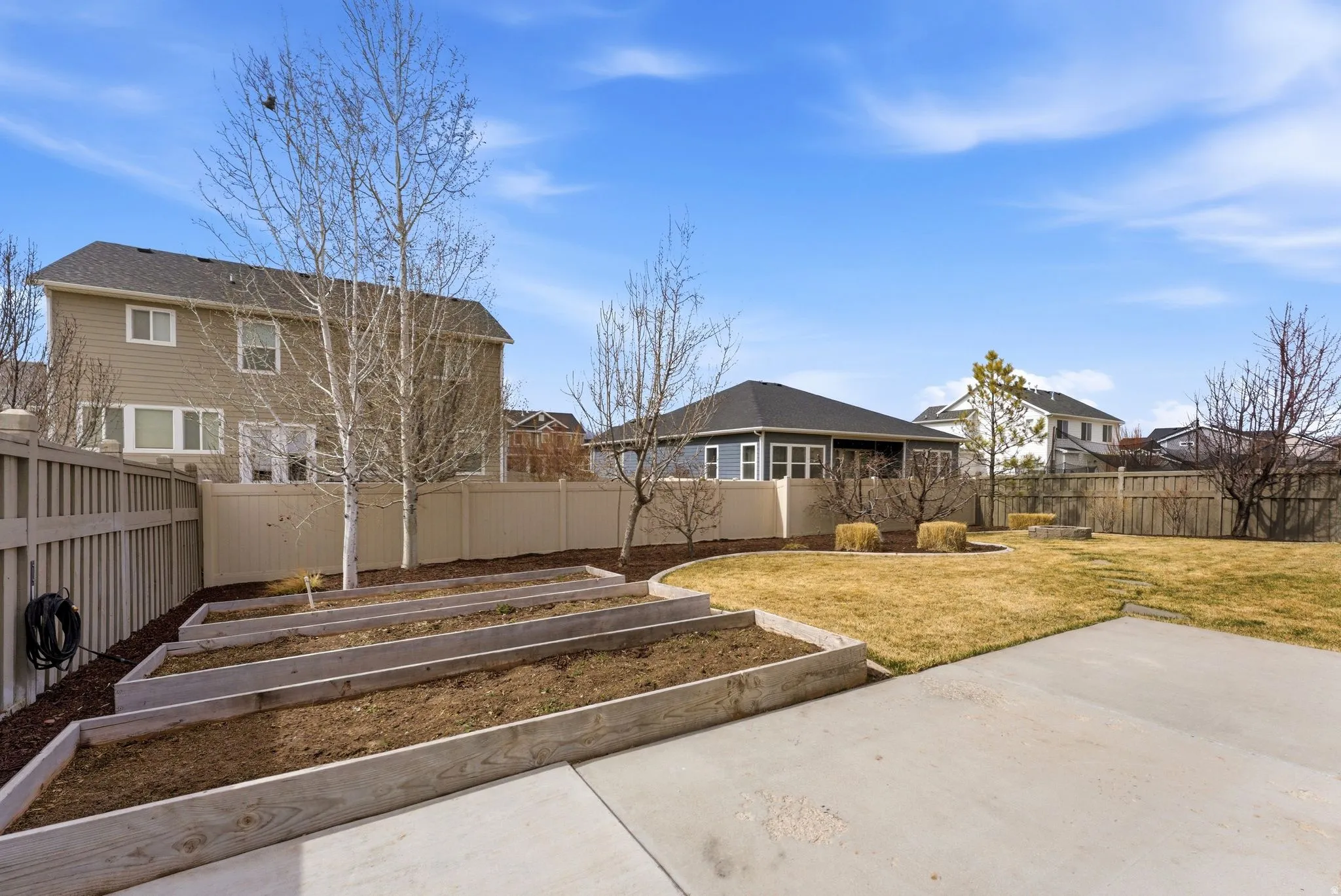 Fenced backyard featuring a vegetable garden and a residential view