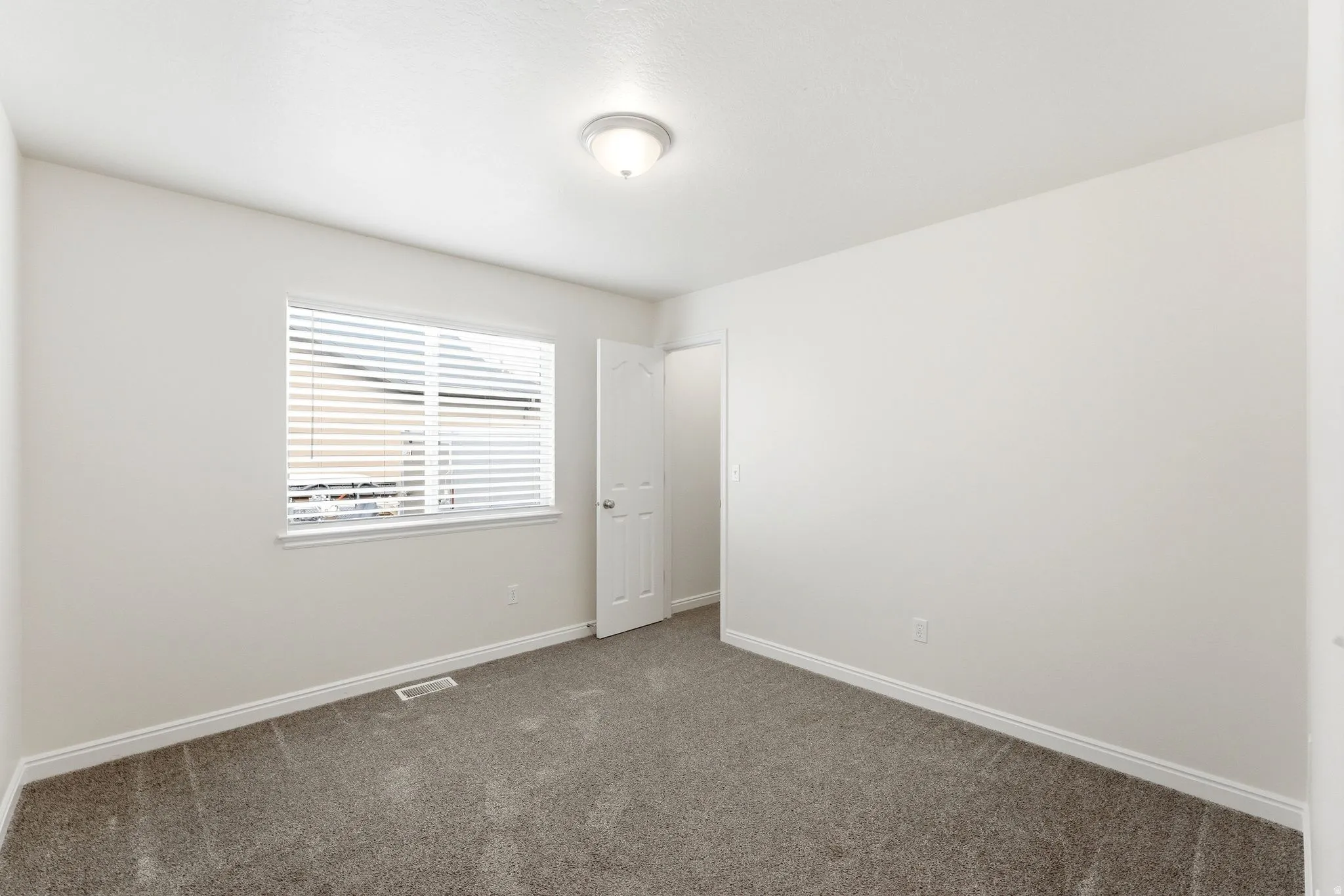 Spare room featuring baseboards and dark carpet
