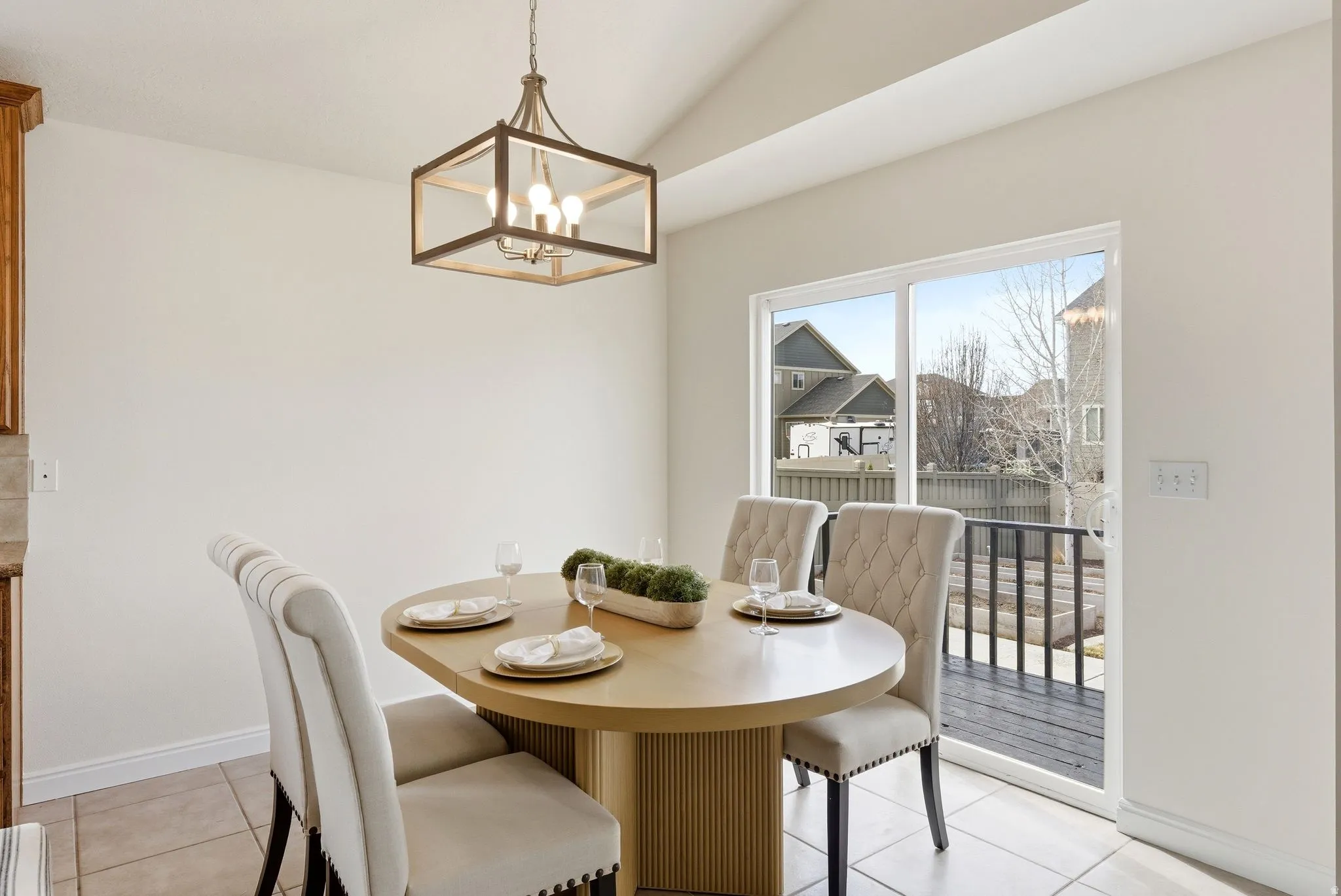 Dining room with hanging lights, vaulted ceiling, and light tile patterned floors