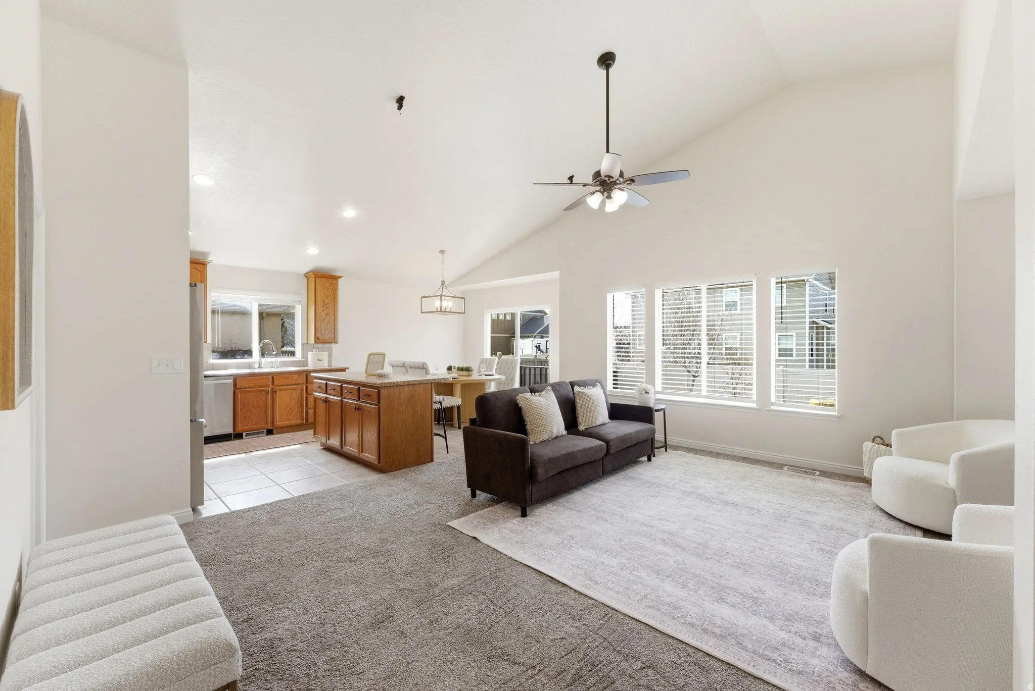 Living area with light colored carpet, ceiling fan, lofted ceiling, and light tile patterned floors
