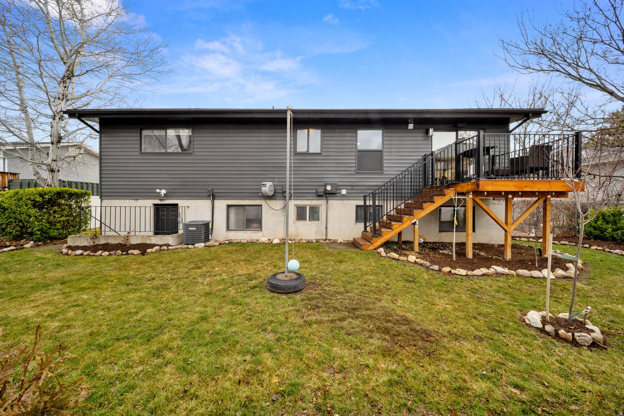 Rear view of house with a wooden deck and a lawn