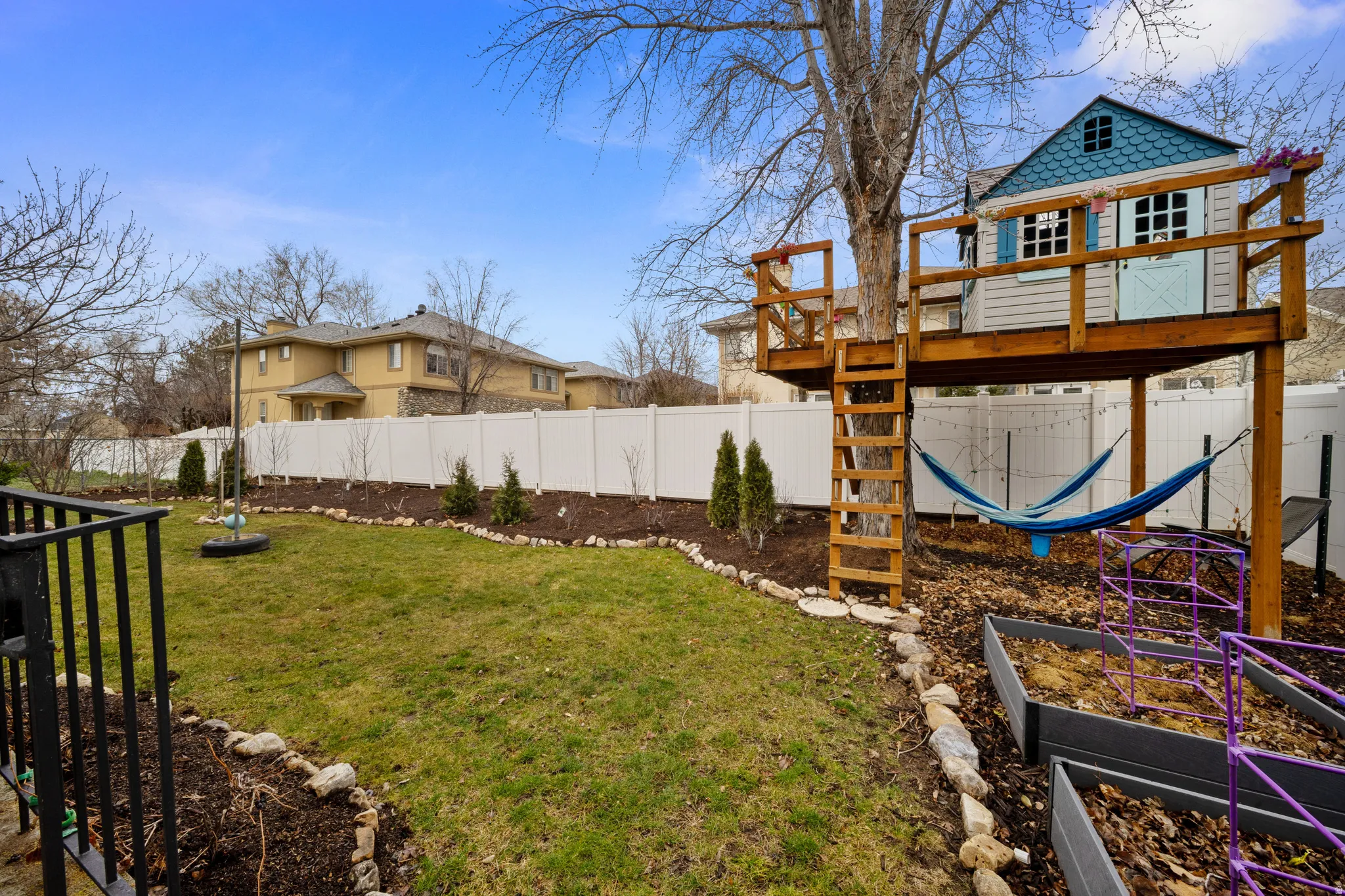 Fenced backyard with a wooden deck and a vegetable garden