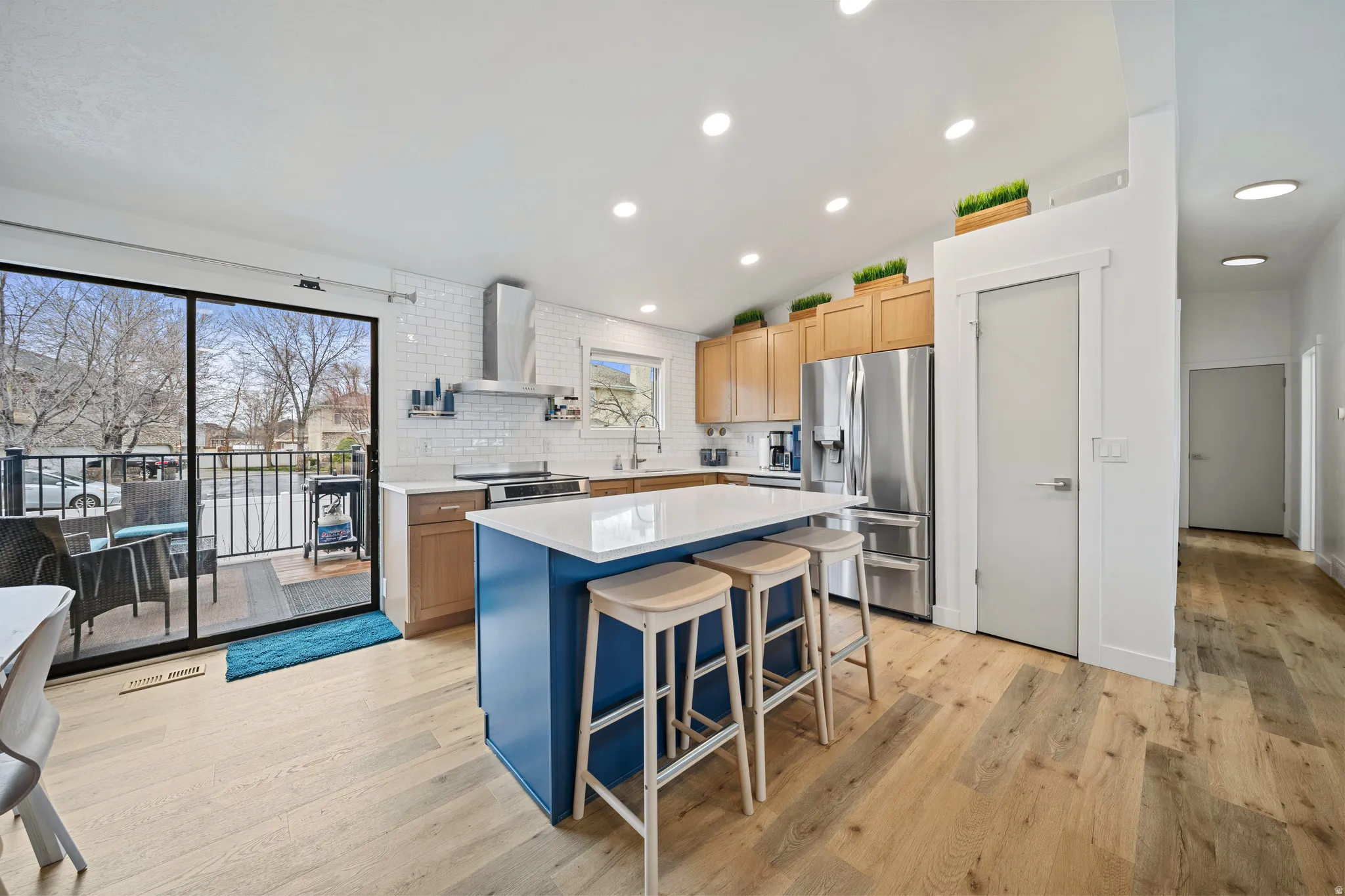 Two tone kitchen with dual tone cabinets, light wood finished floors, stainless steel appliances, a kitchen island, and a kitchen breakfast bar