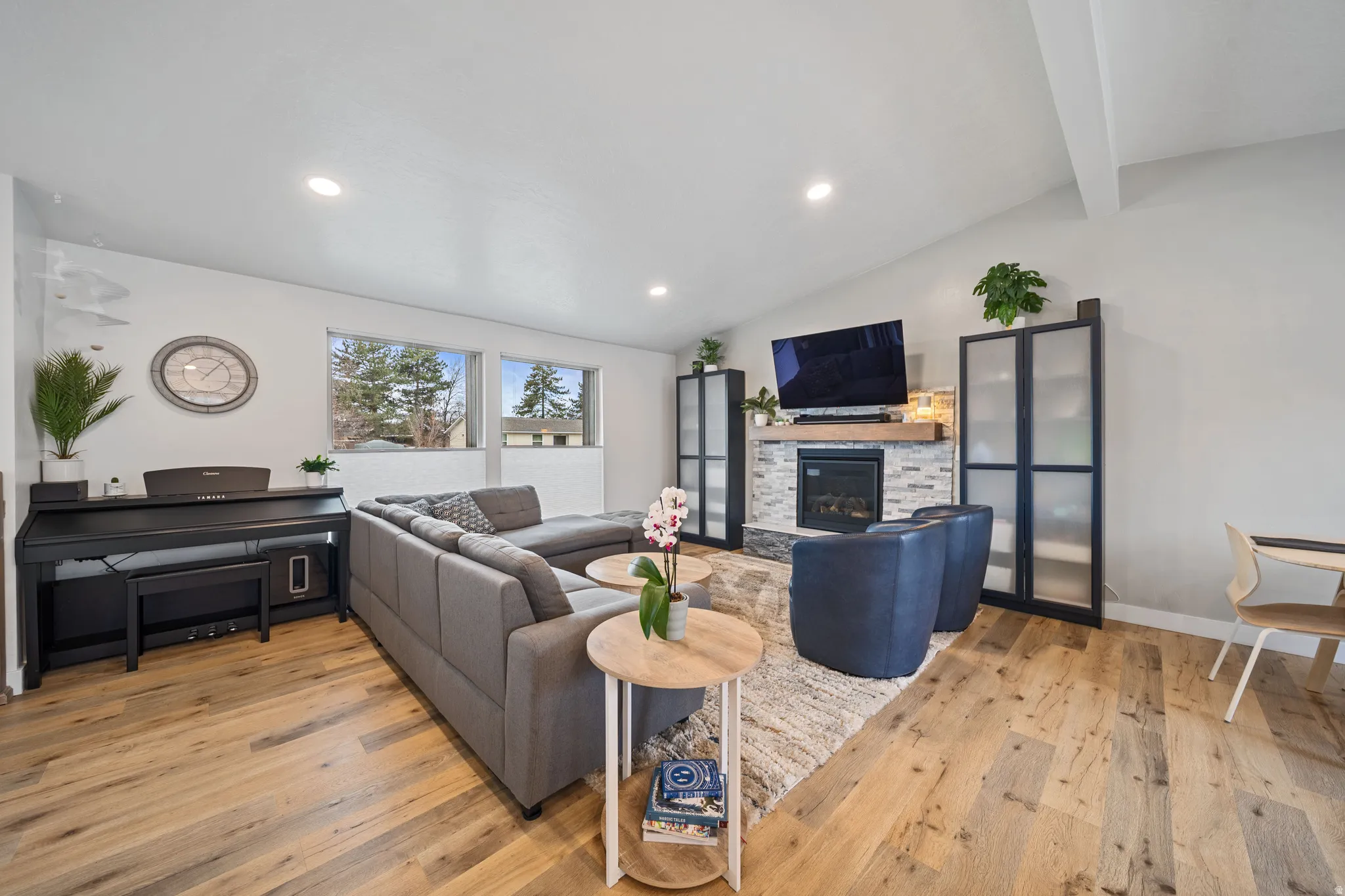 Living room with light wood-style floors, lofted ceiling with beams, a fireplace, and recessed lighting