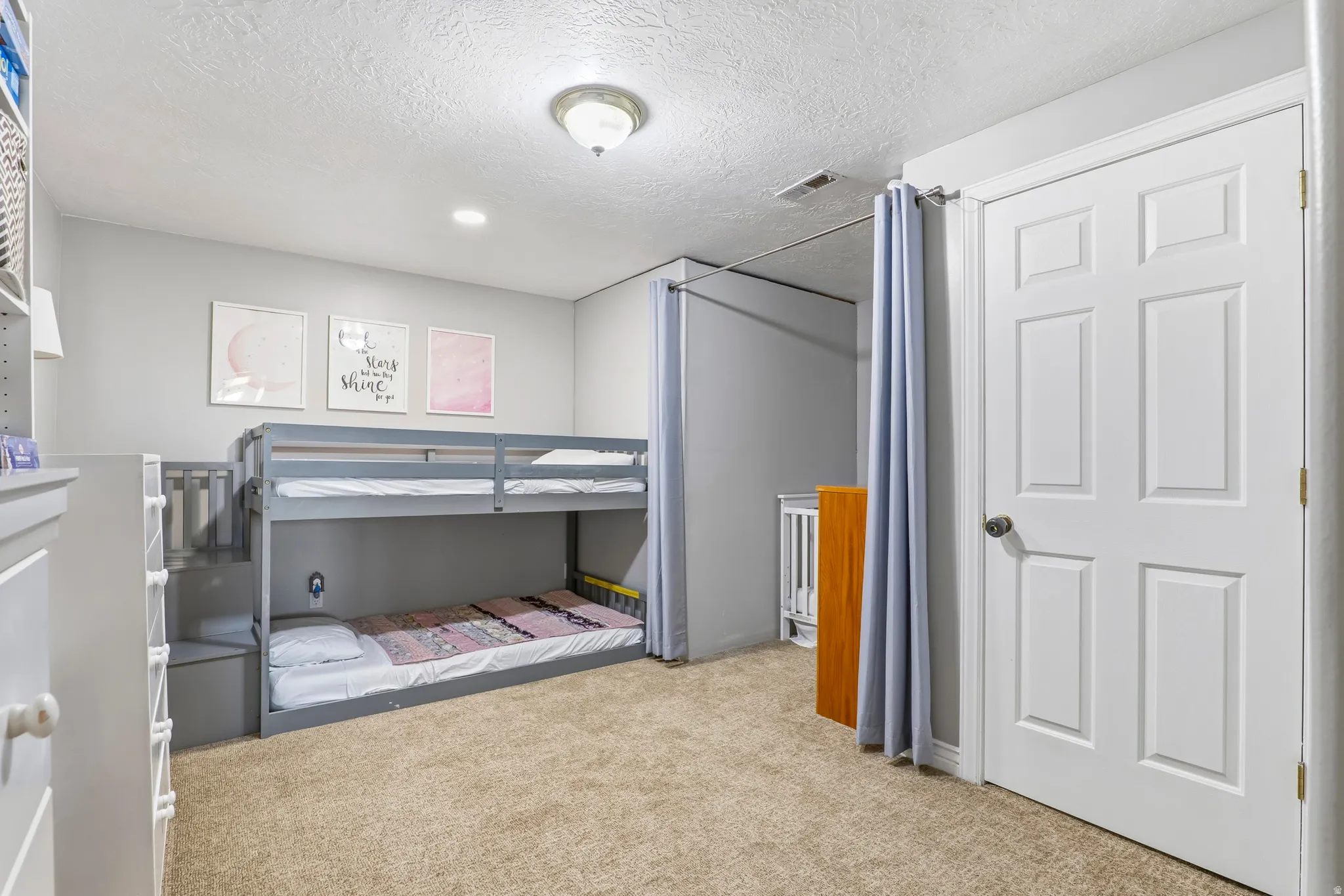 Bedroom featuring light colored carpet and a textured ceiling