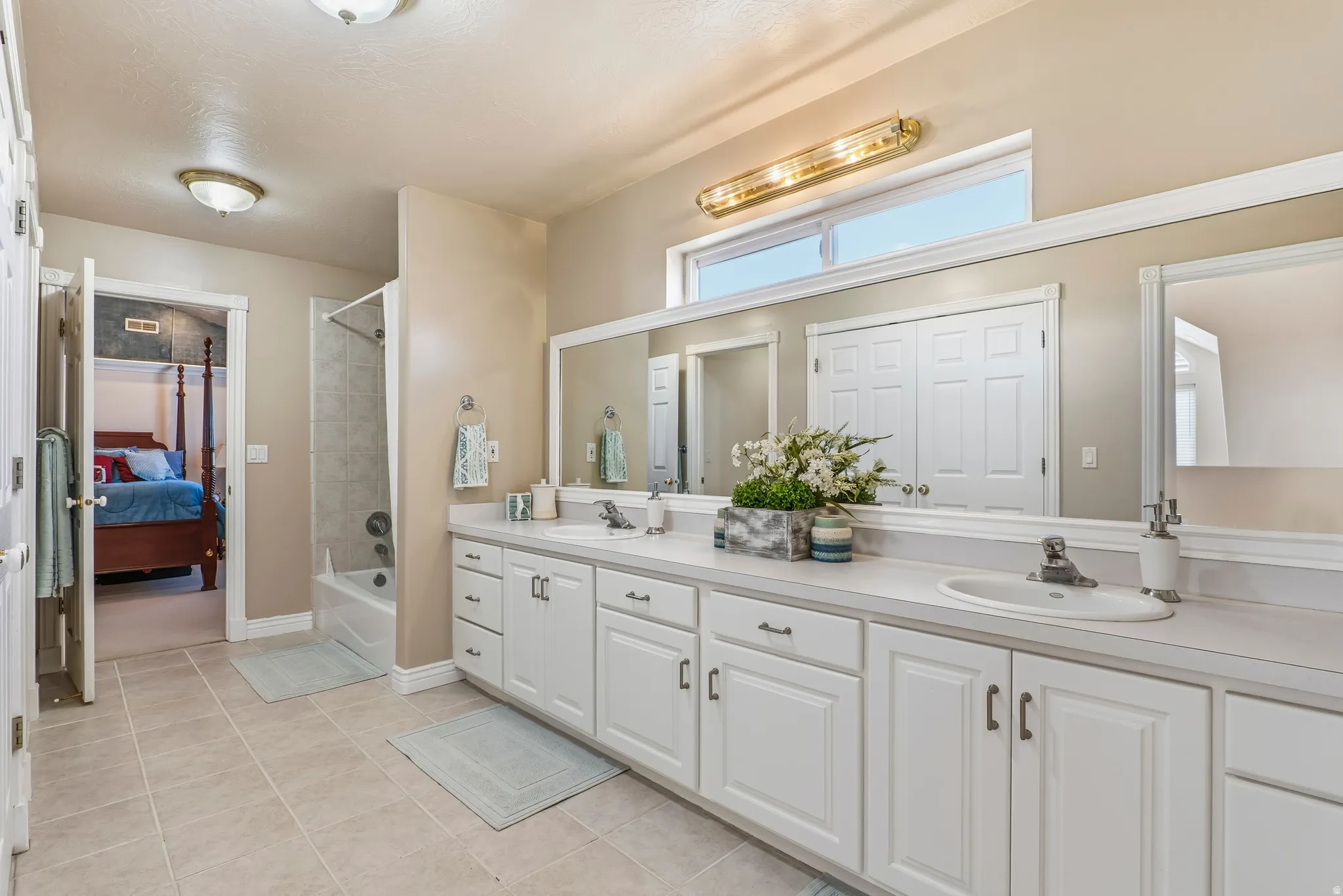 Ensuite bathroom featuring double vanity, tub / shower combination, and light tile patterned floors
