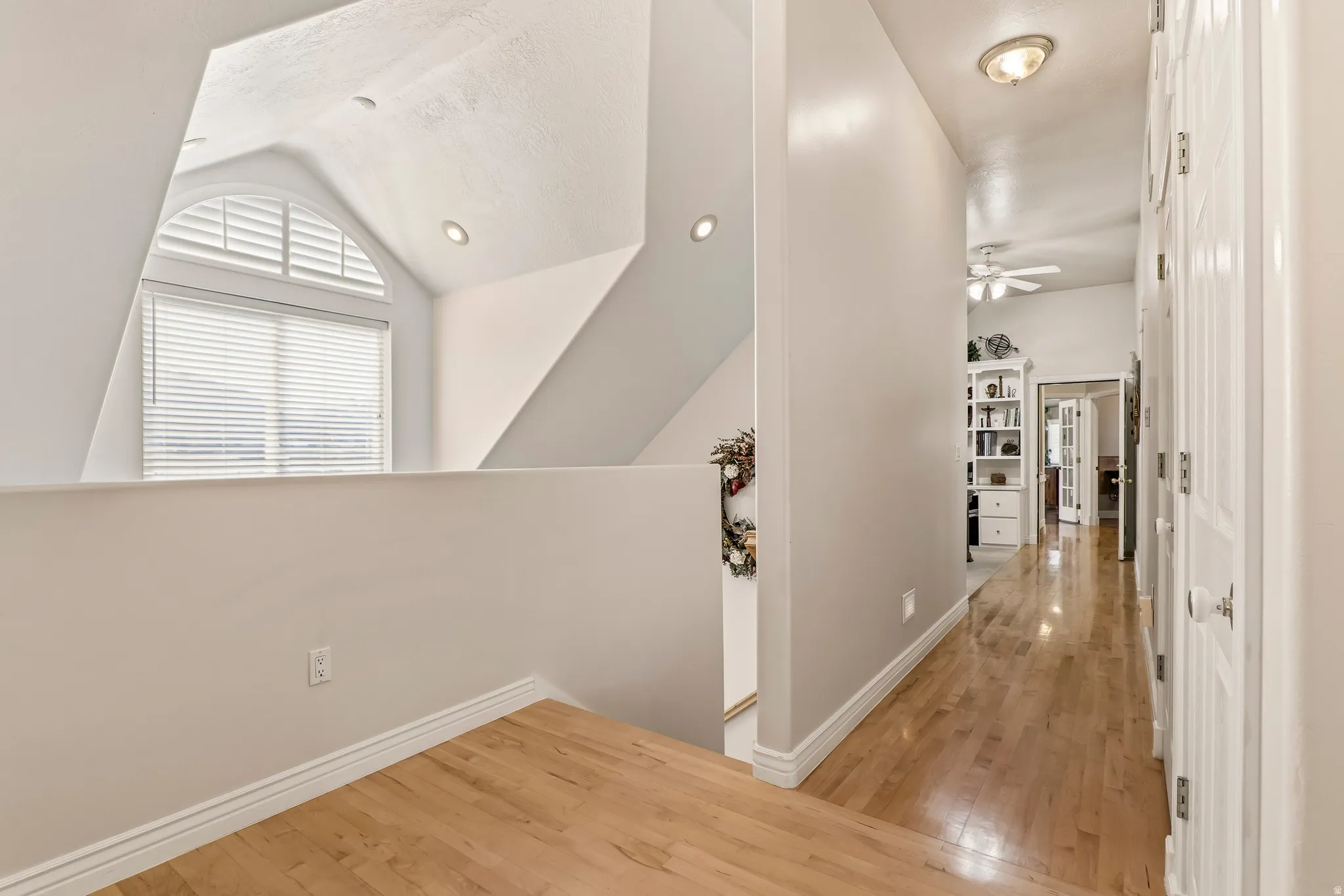 Corridor featuring light wood finished floors and lofted ceiling