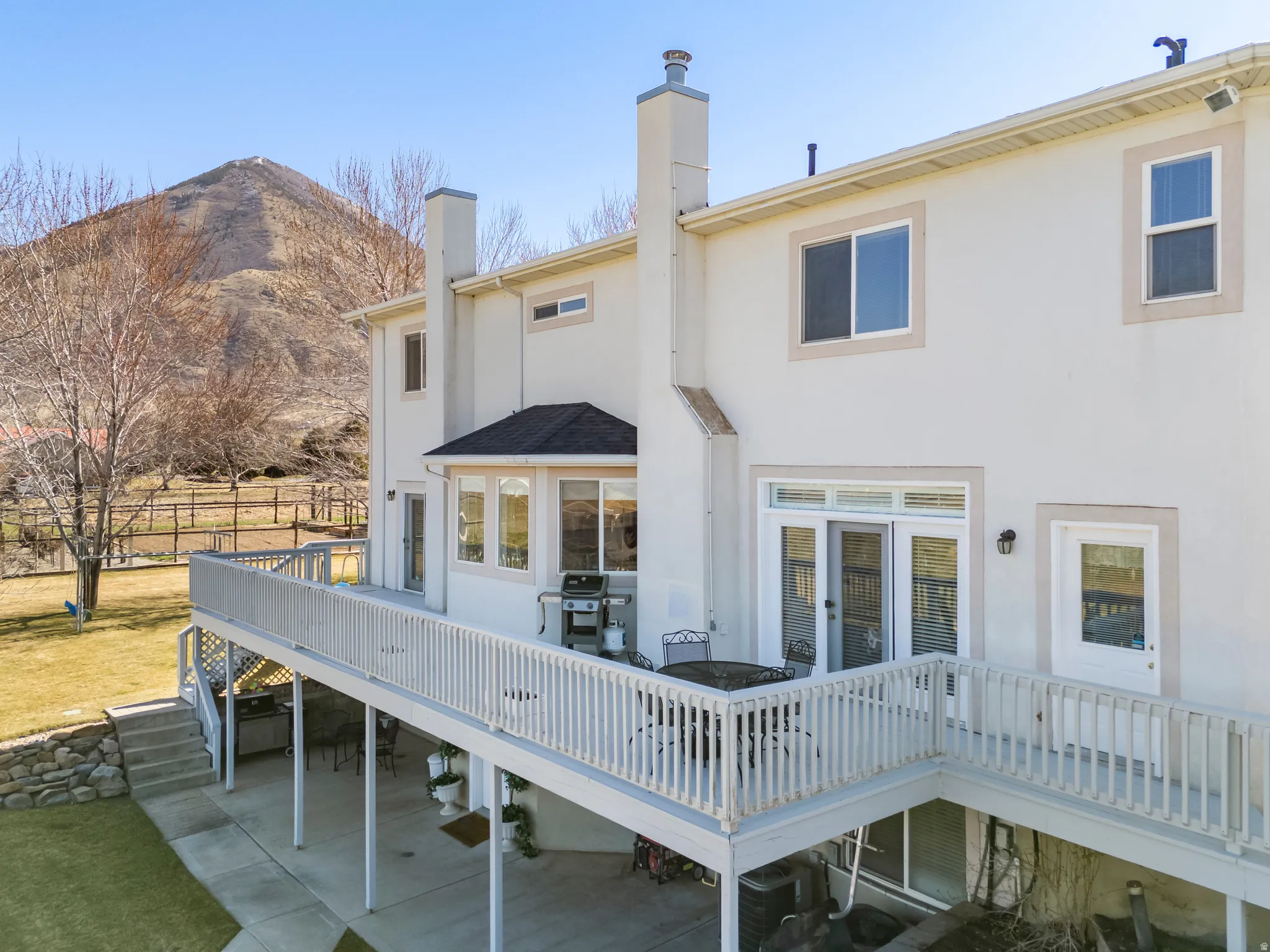 Rear view of house featuring a deck with mountain view, a chimney, stucco siding, and french doors