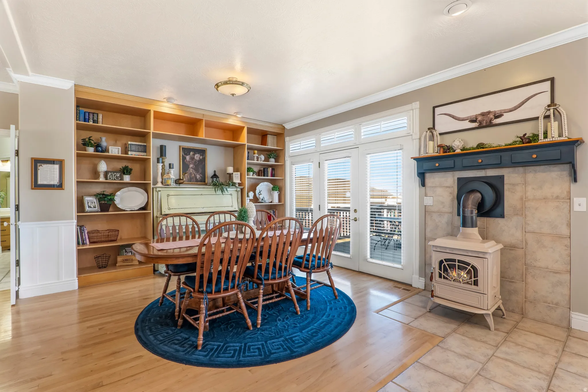 Dining room with ornamental molding, built in shelves, a wood stove, and light wood finished floors
