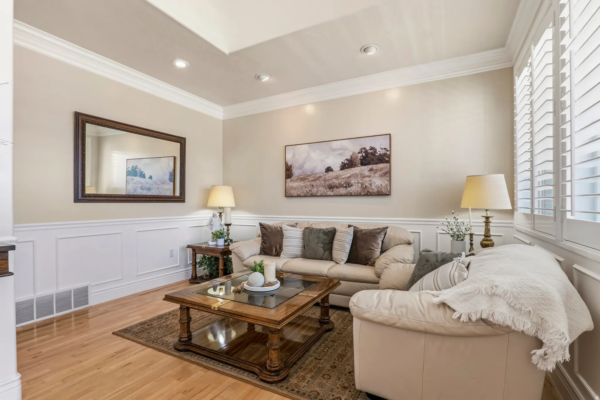 Living area featuring crown molding, light wood-style floors, a decorative wall, and a wainscoted wall