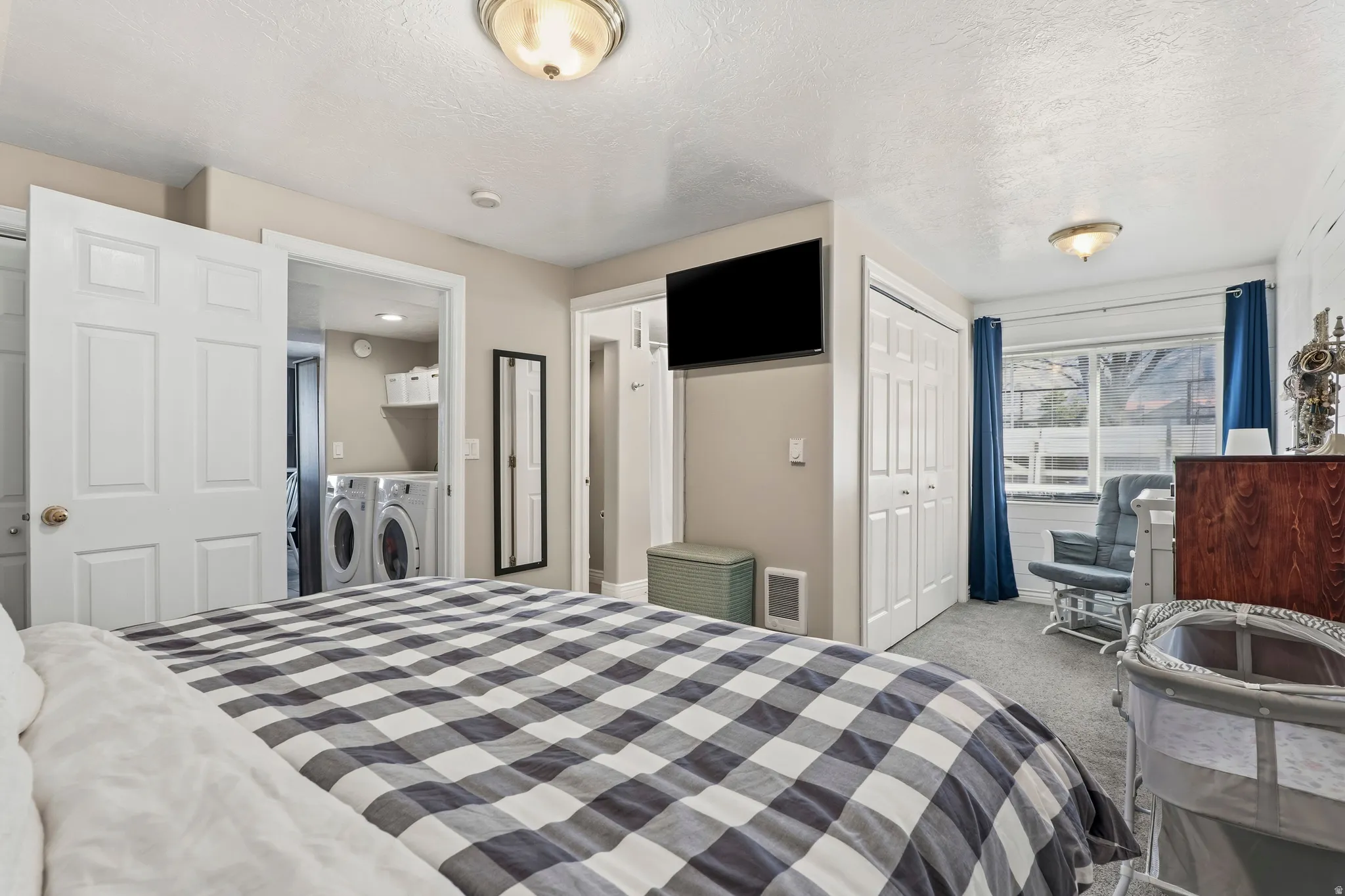Bedroom featuring a closet, light colored carpet, washing machine and clothes dryer, and a textured ceiling