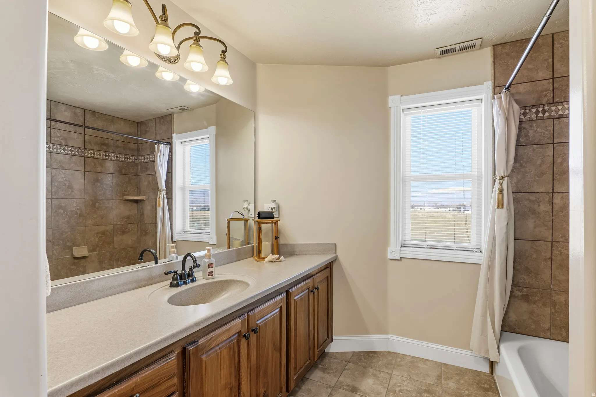 Bathroom featuring vanity, shower / bath combination with curtain, and light tile patterned floors