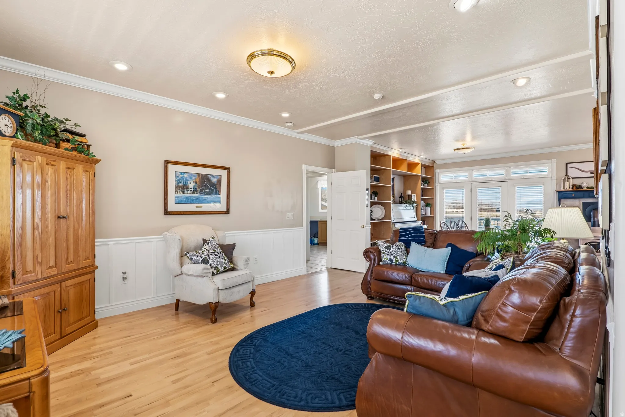 Living area with a wainscoted wall, ornamental molding, light wood-style floors, and recessed lighting