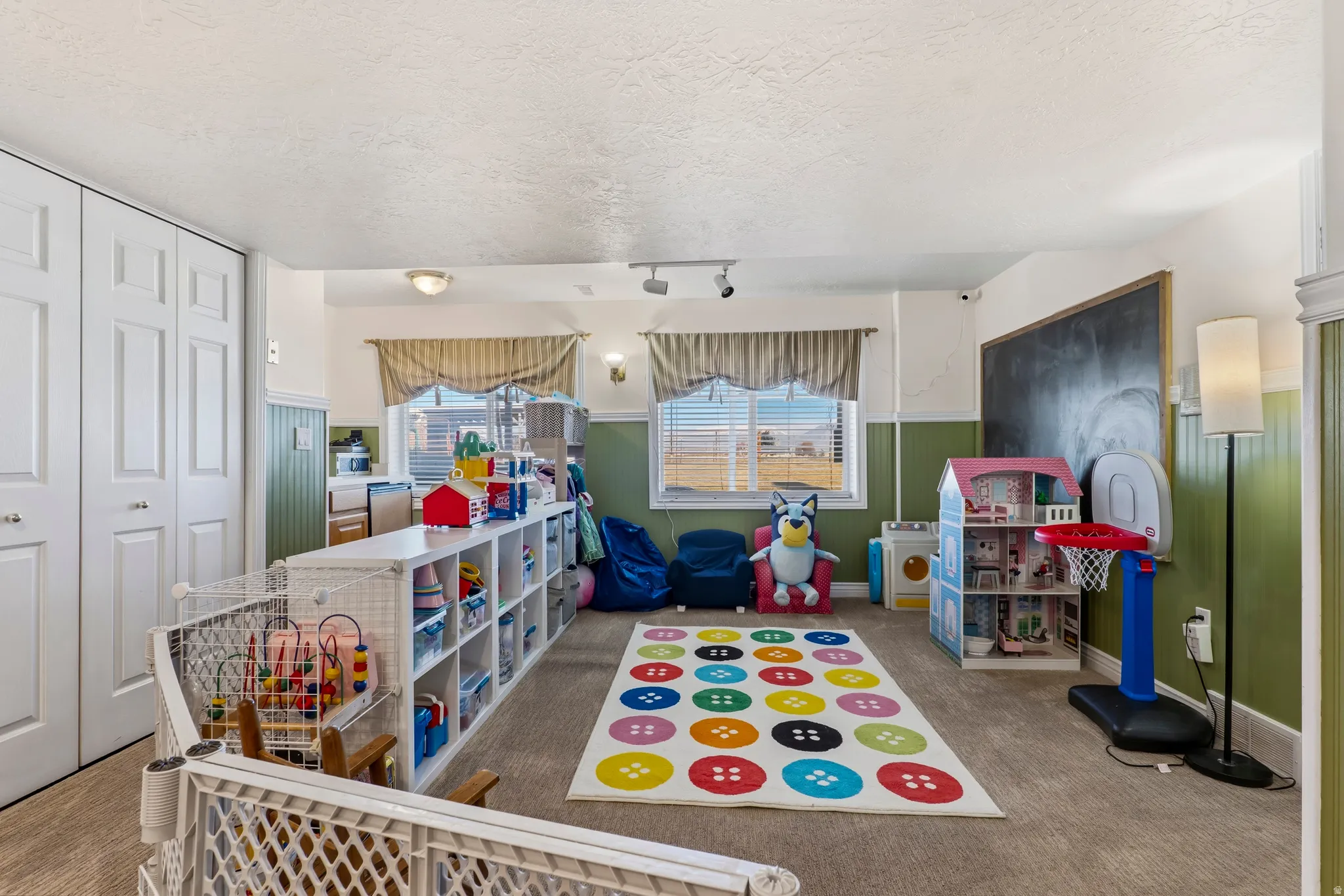 Playroom featuring a textured ceiling, a wainscoted wall, and track lighting