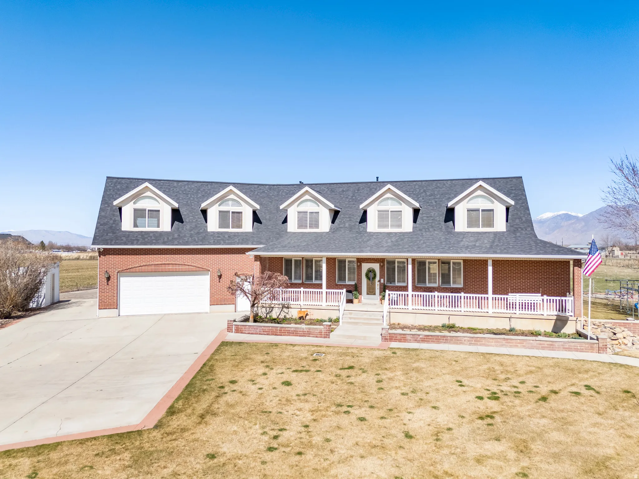 Cape cod house featuring a mountain view, covered porch, brick siding, and driveway