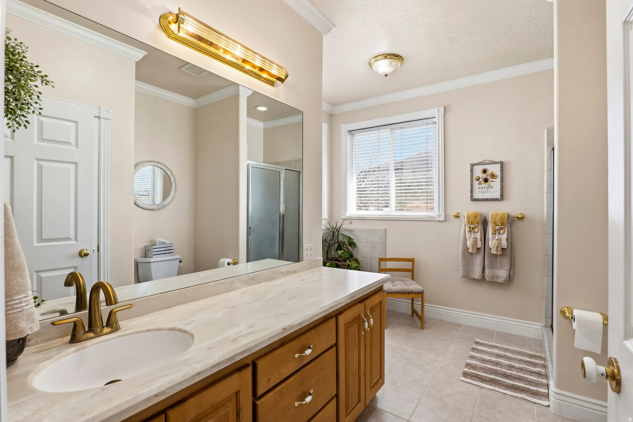 Full bathroom with a stall shower, crown molding, vanity, and light tile patterned flooring