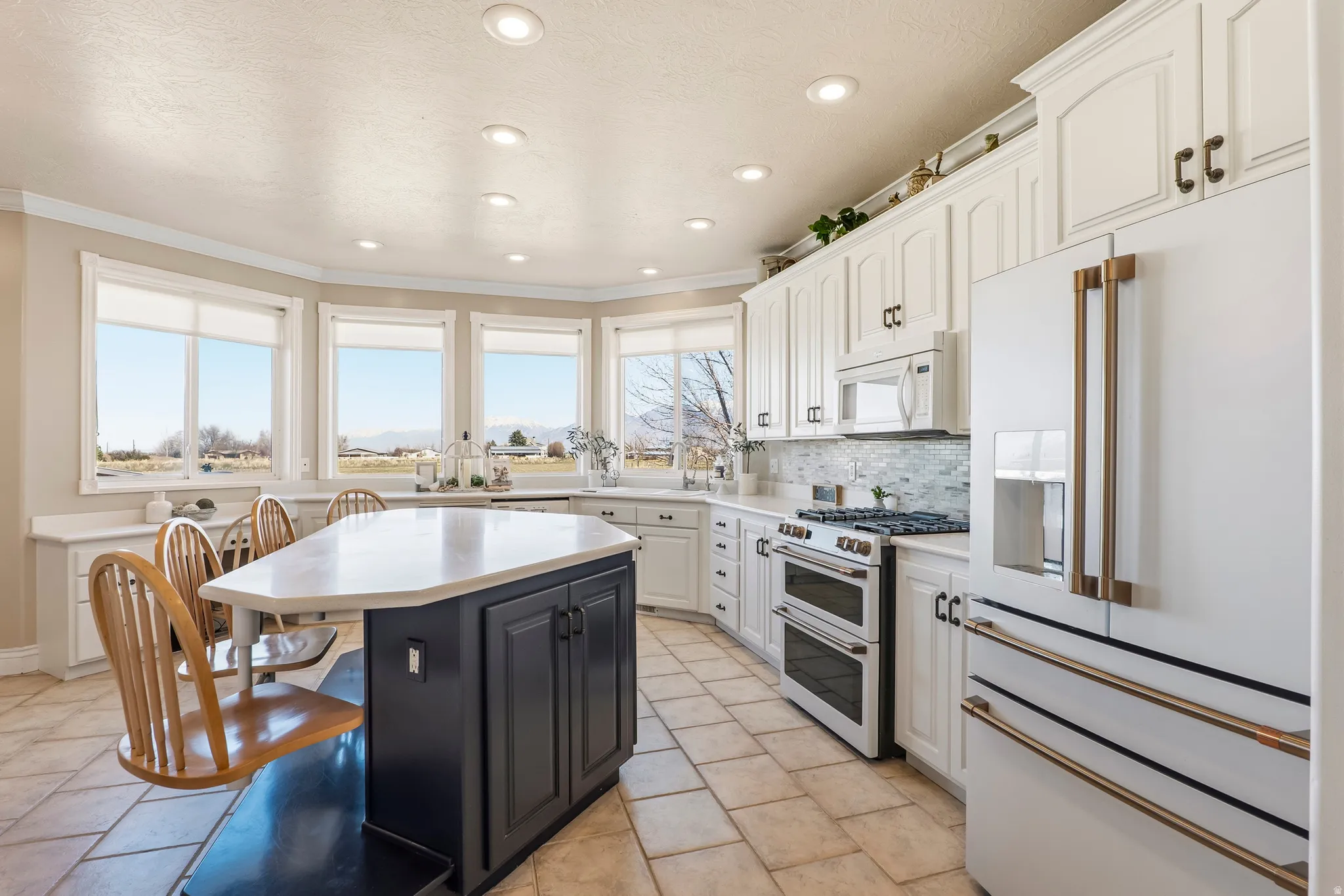 Kitchen featuring white appliances, dual tone cabinetry, a breakfast bar area, decorative backsplash, and ornamental molding
