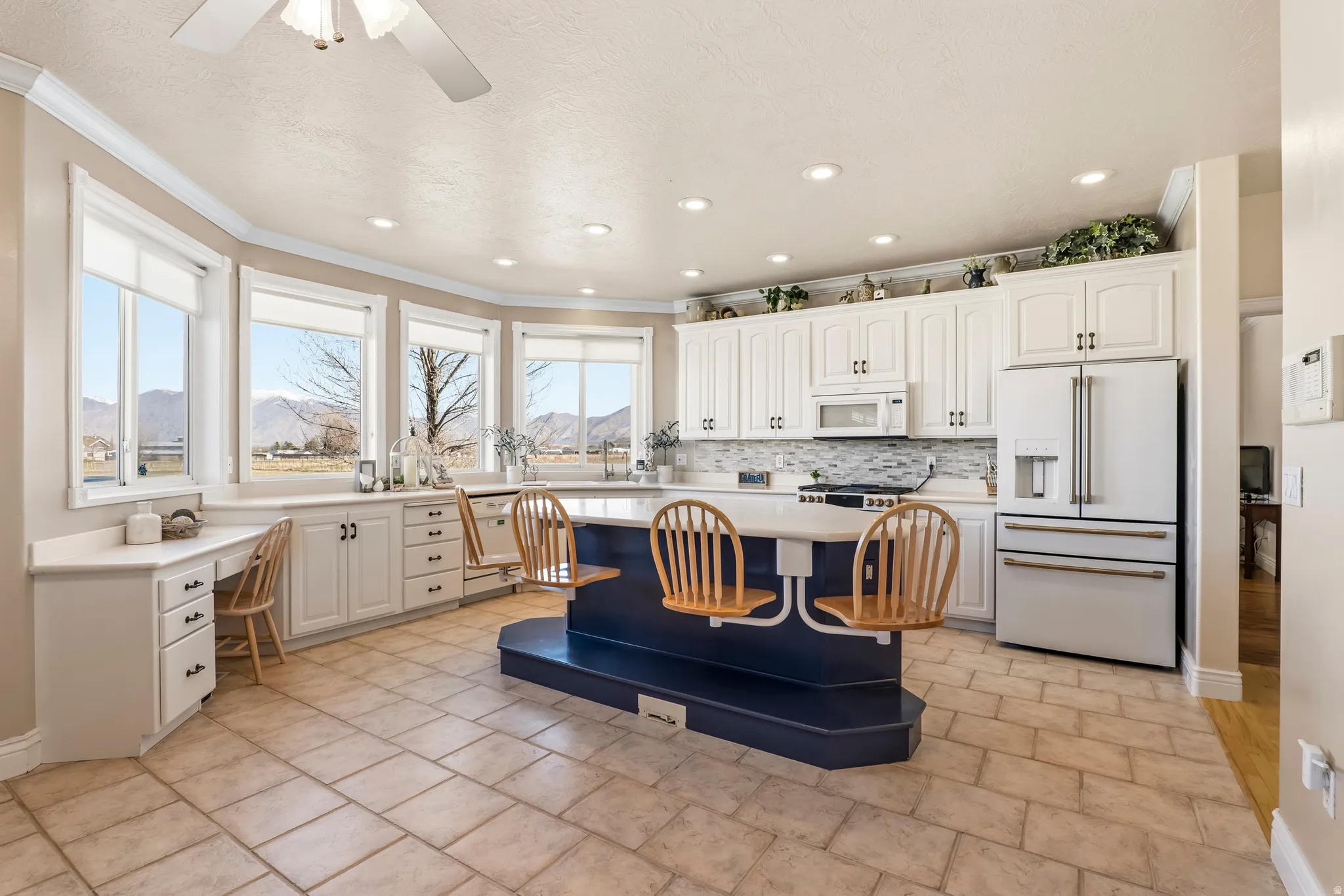 Kitchen with white appliances, light countertops, a mountain view, a kitchen island, and a ceiling fan