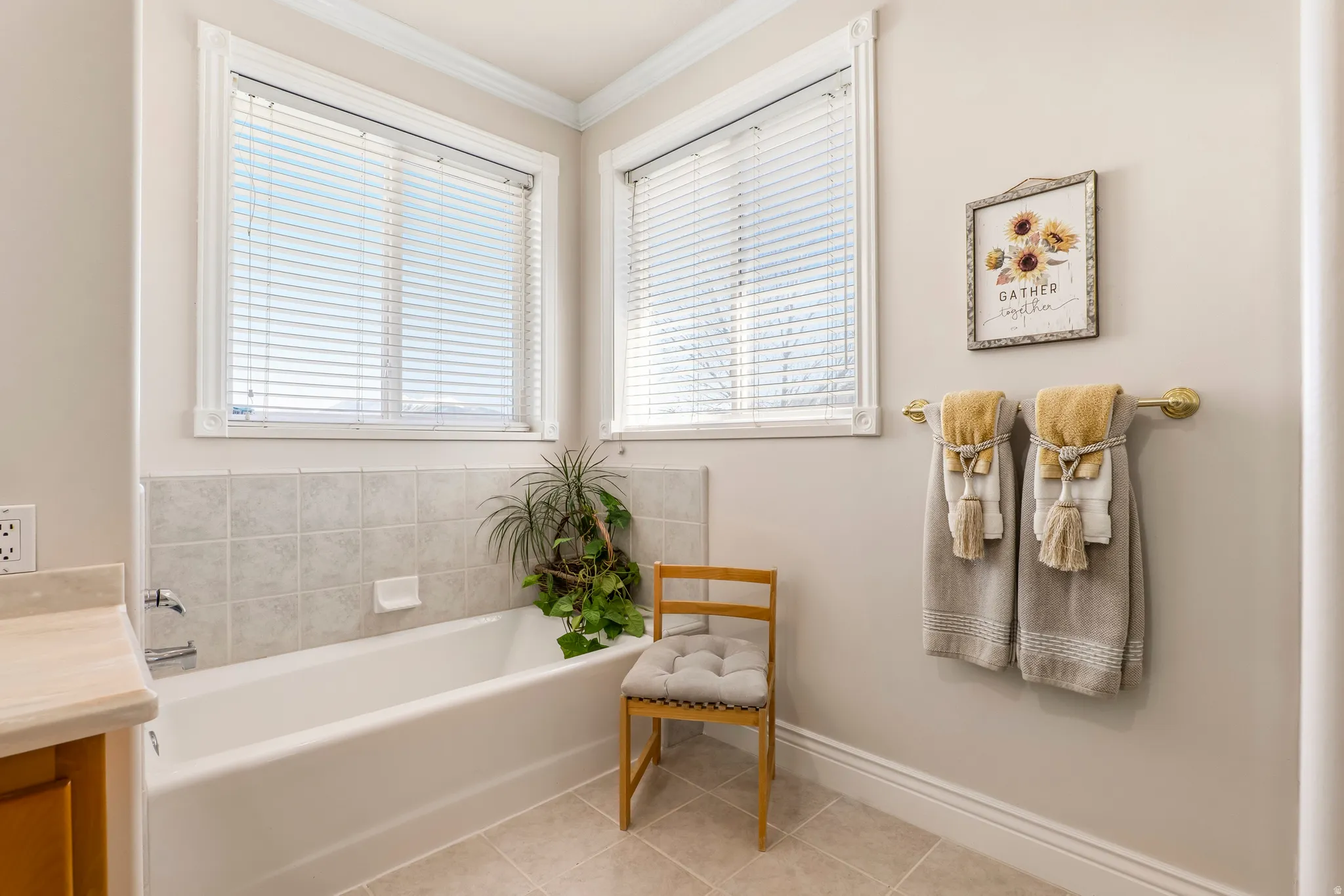 Bathroom with vanity, a garden tub, crown molding, and light tile patterned floors