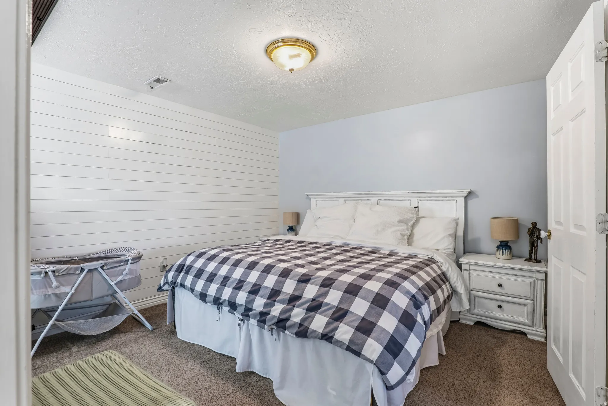 Bedroom featuring dark colored carpet, a textured ceiling, and wooden walls